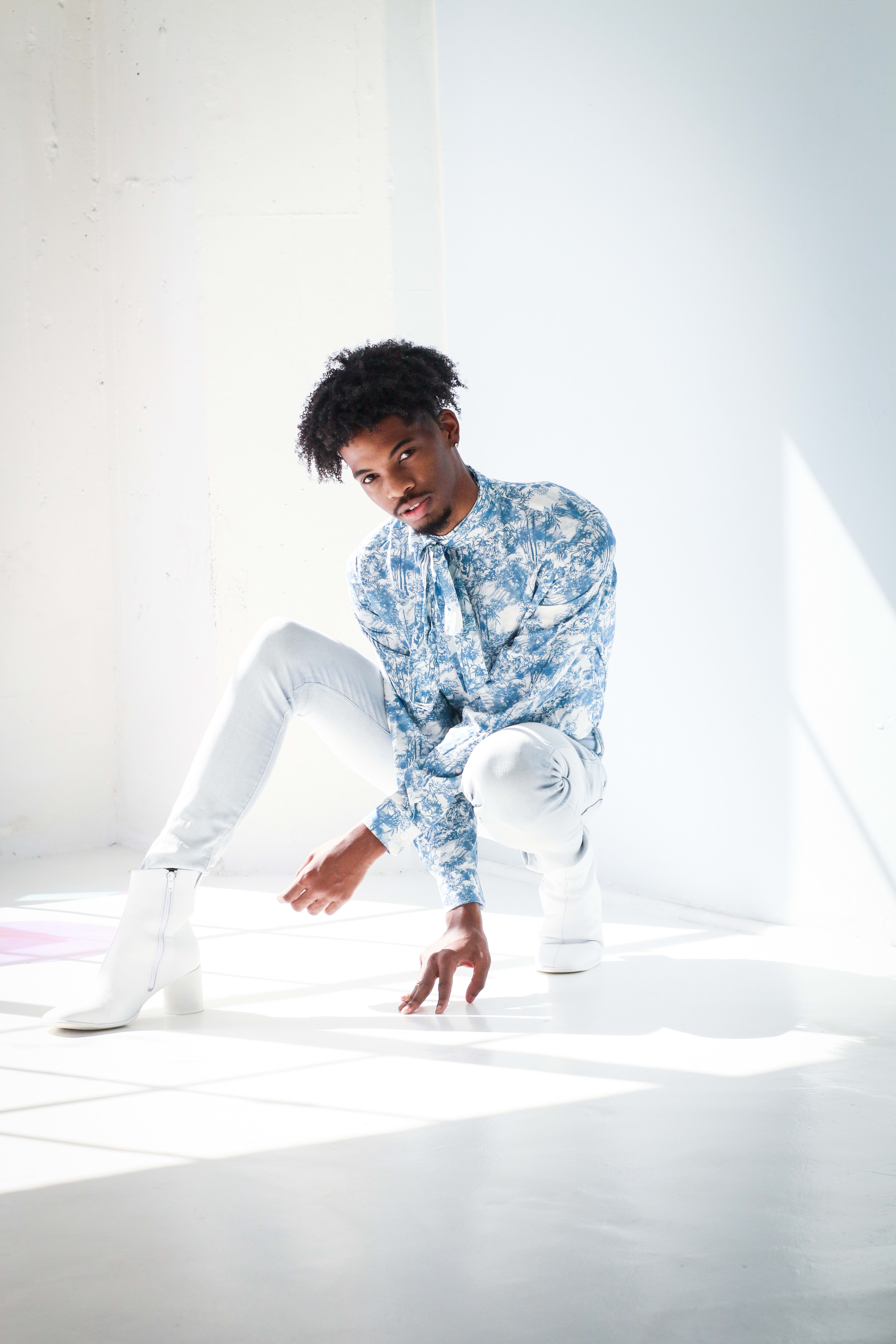 A fashion photoshoot featuring a man in blue shirt and white pants.