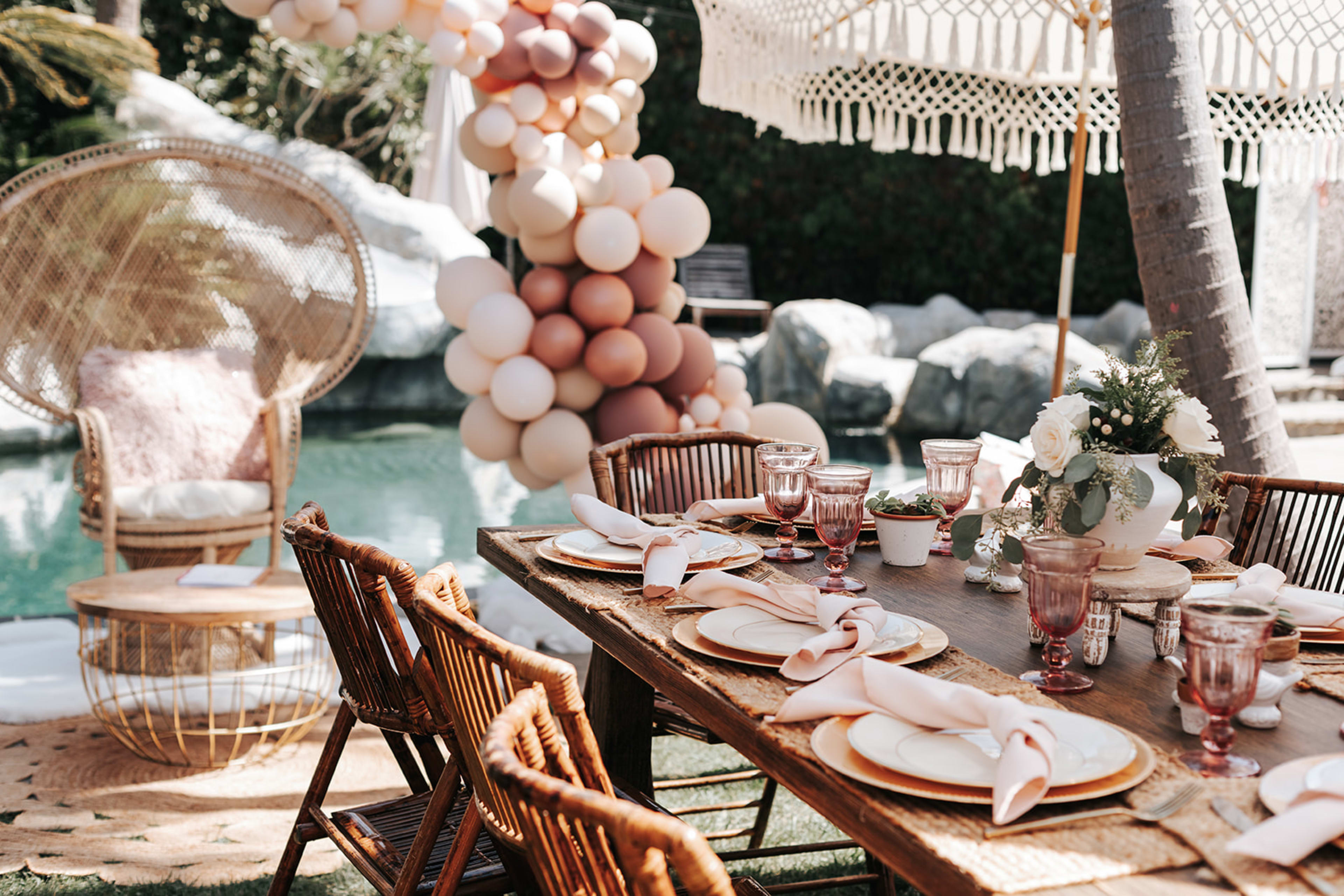 Ein im Boho-Stil gedeckter Tisch für eine Party neben einem Pool.