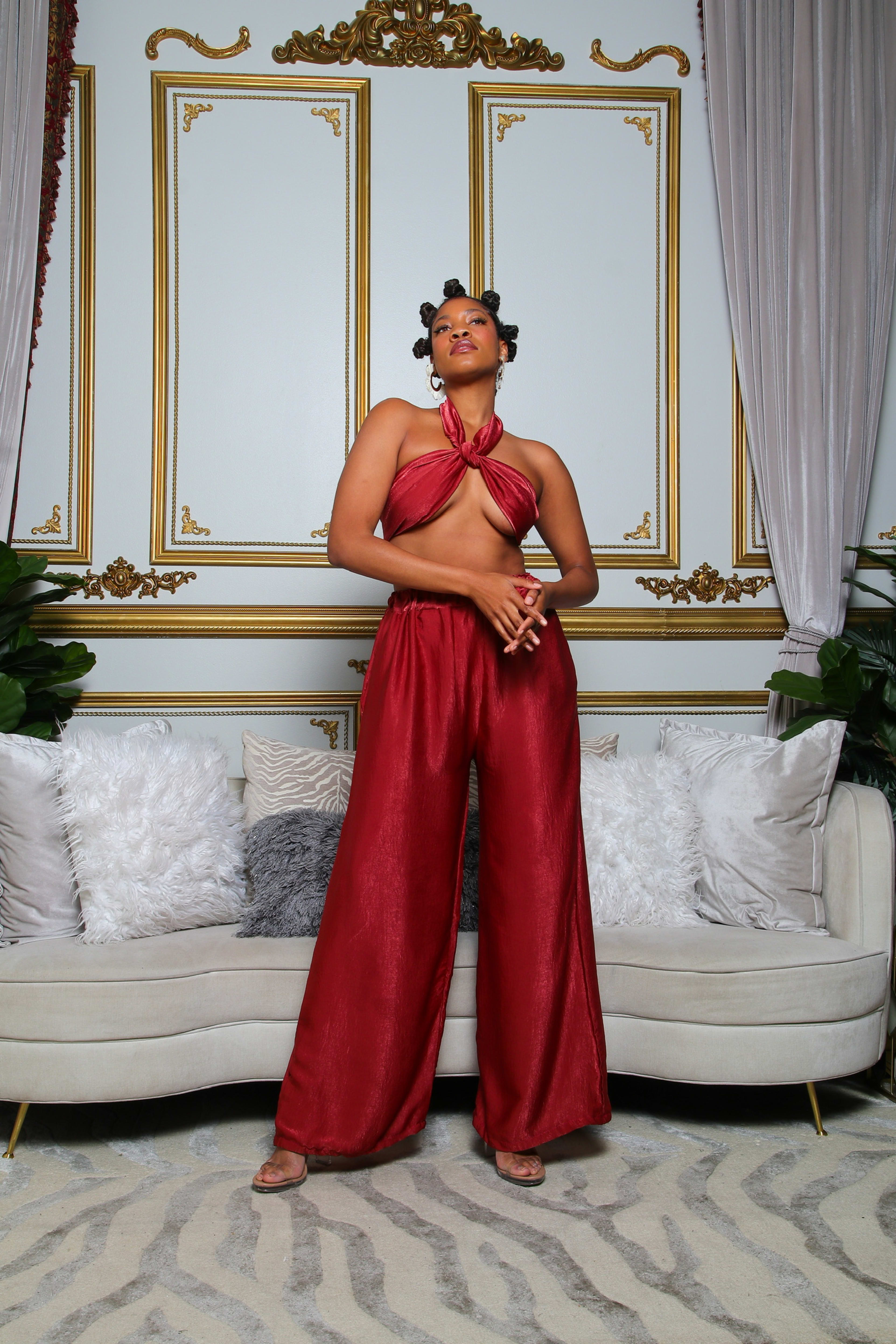 A fashion-conscious woman wearing red strikes a pose in front of a couch during her photoshoot.