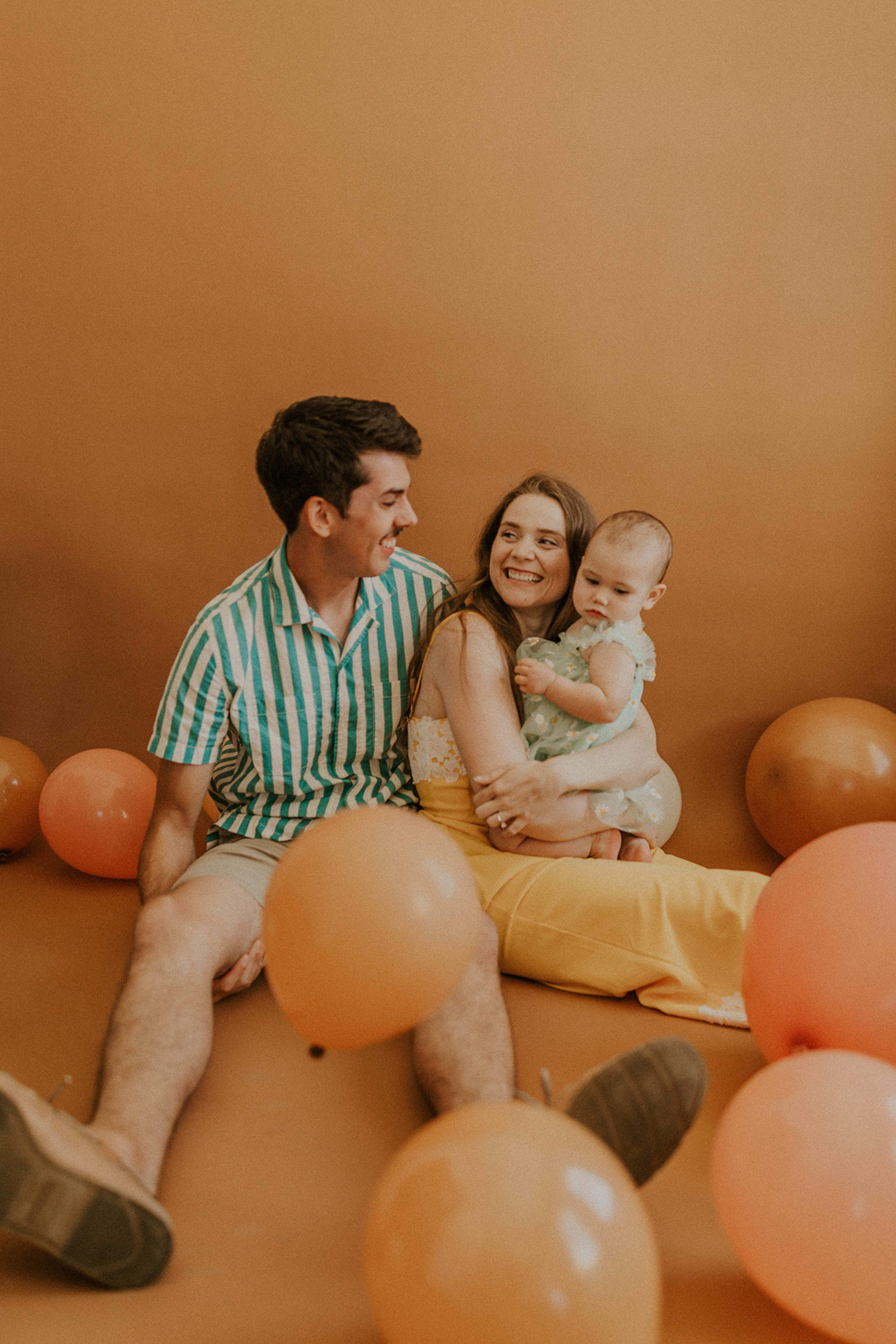 Family photo with orange balloons and seamless backdrop