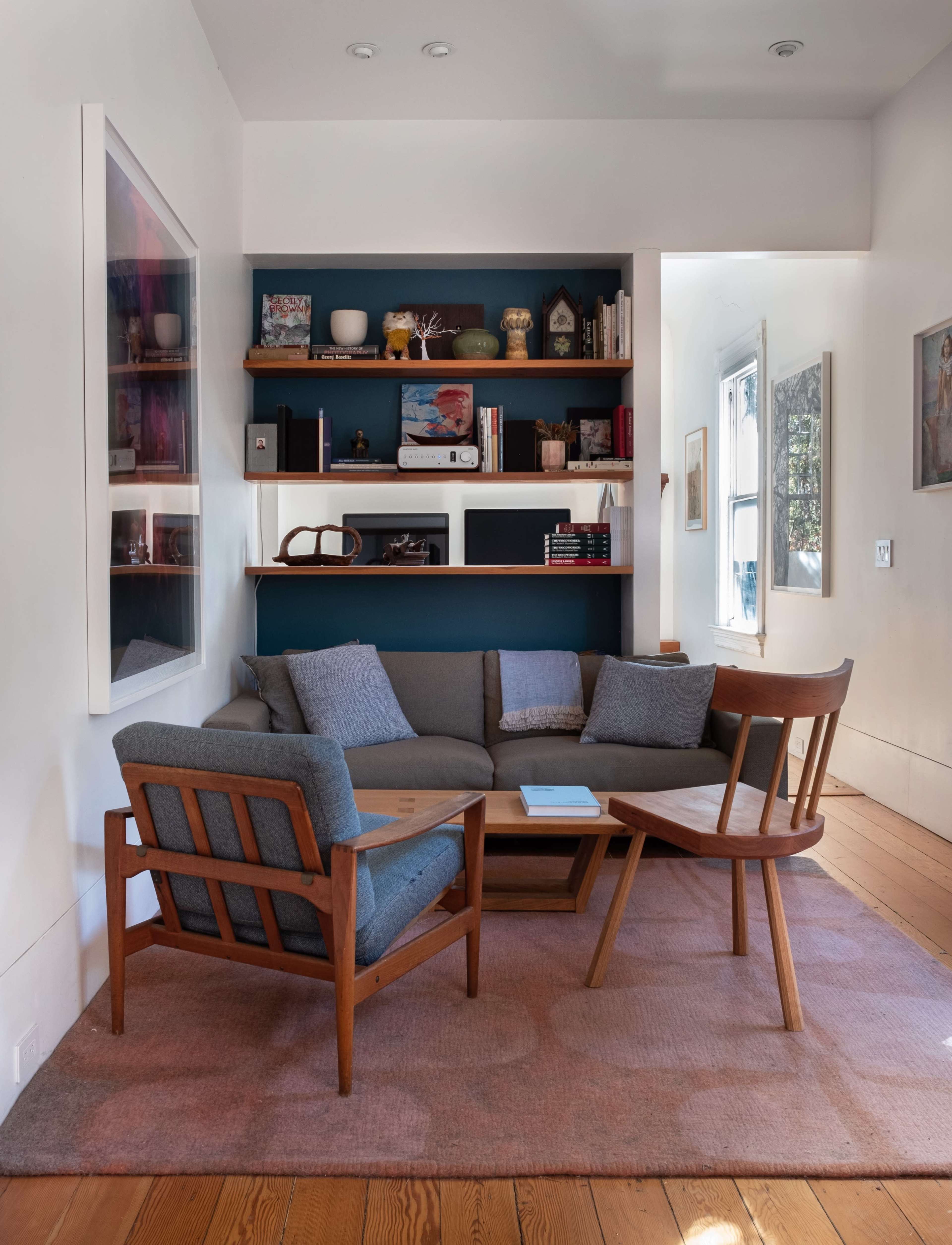 The image shows a modern living room with a gray sectional sofa, a wooden coffee table, and a chair, arranged around a small area rug.