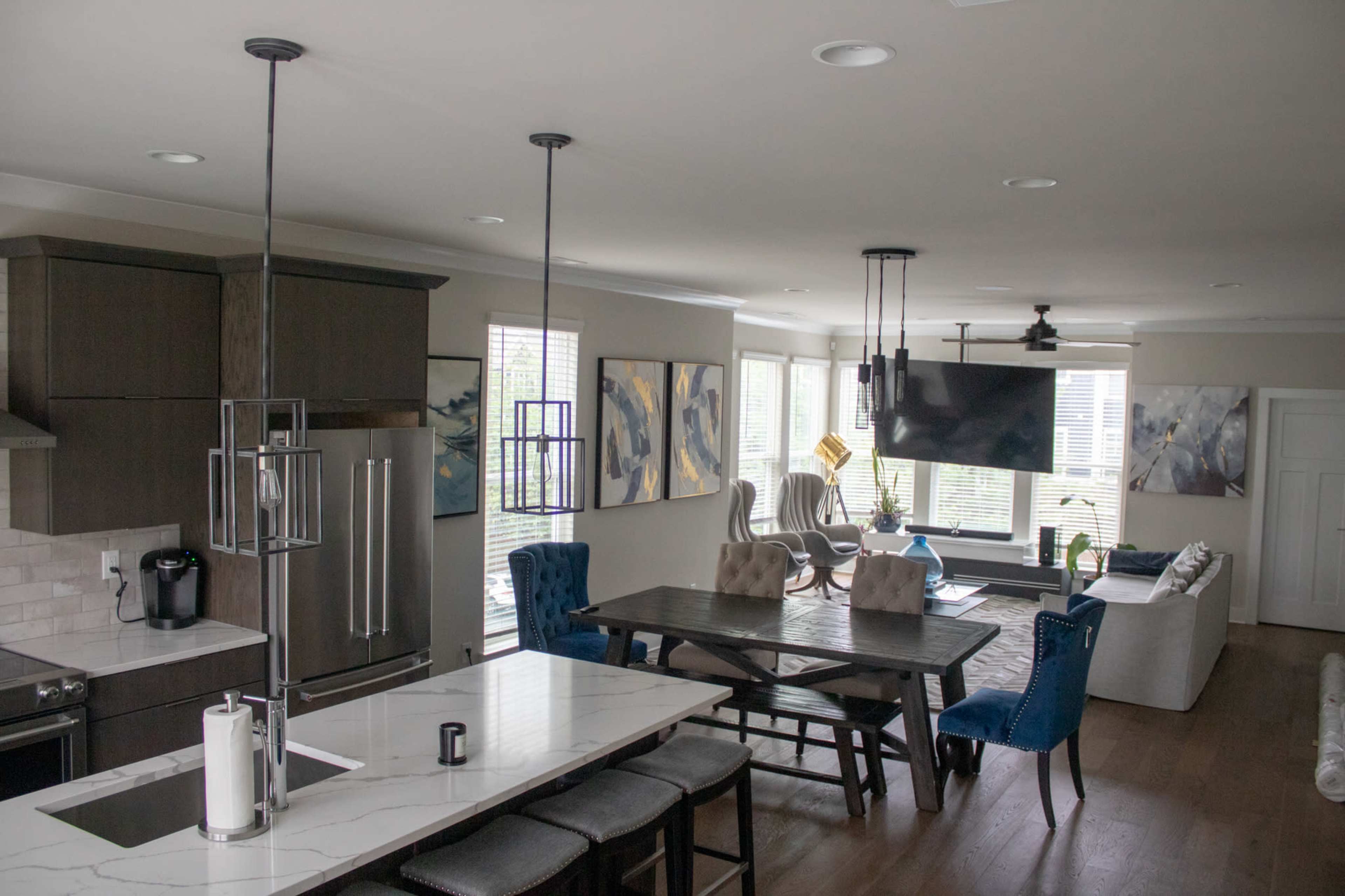 A modern open-concept living and dining area with a kitchen, large windows, a dining table, and a seating area featuring a television.