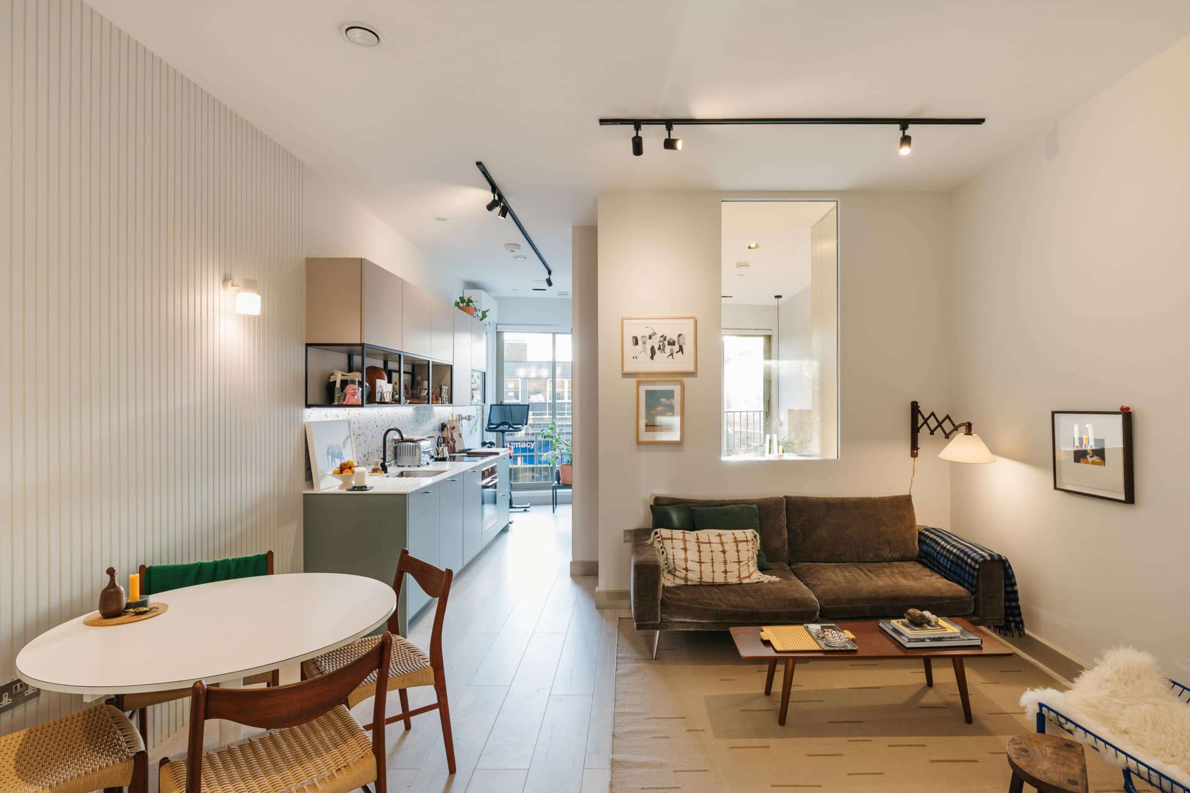 A modern open-concept living space features a kitchen and dining area, with a cozy seating area showcasing a sofa and a coffee table.