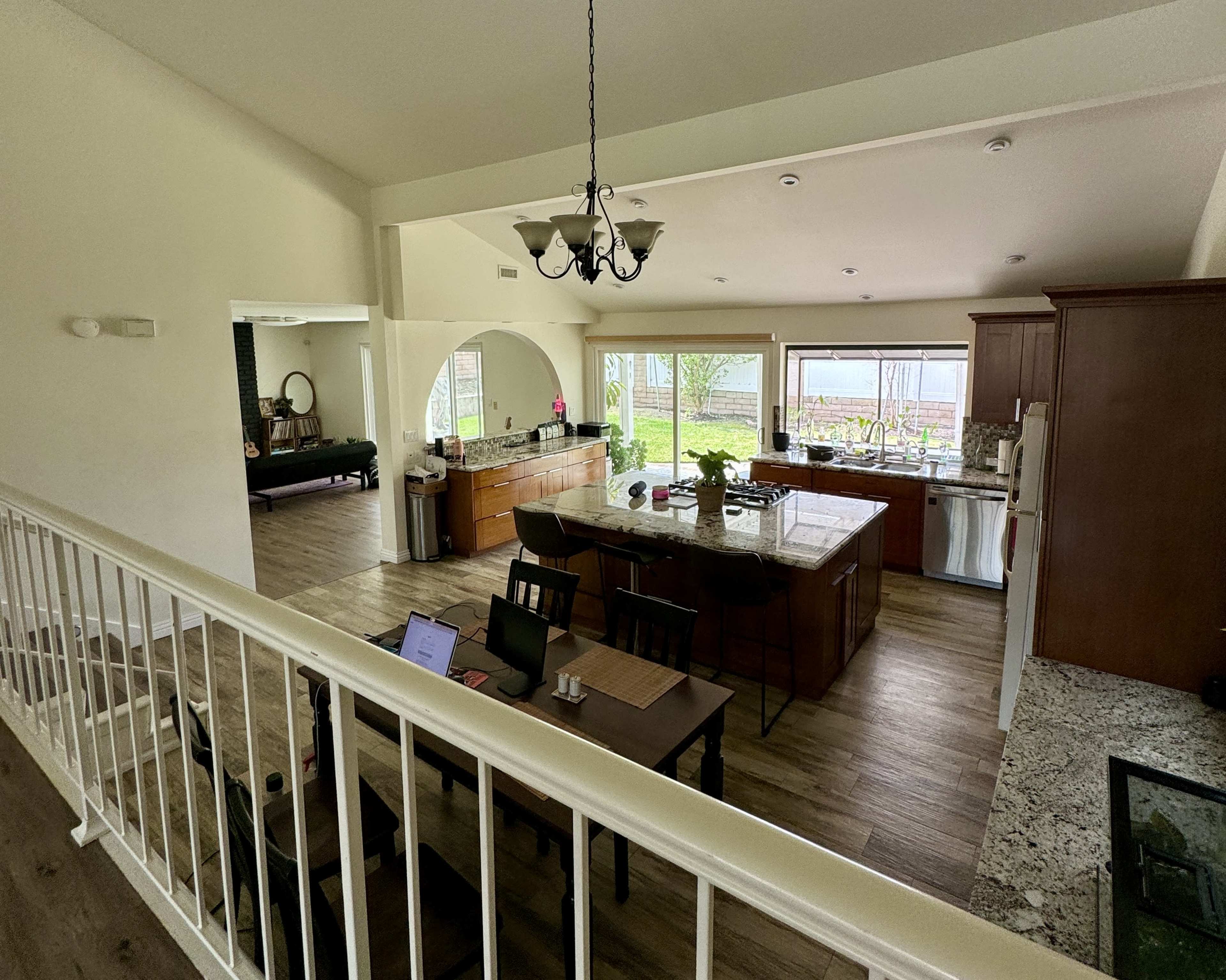 A spacious kitchen and dining area feature wooden cabinetry, granite countertops, and large windows allowing natural light.