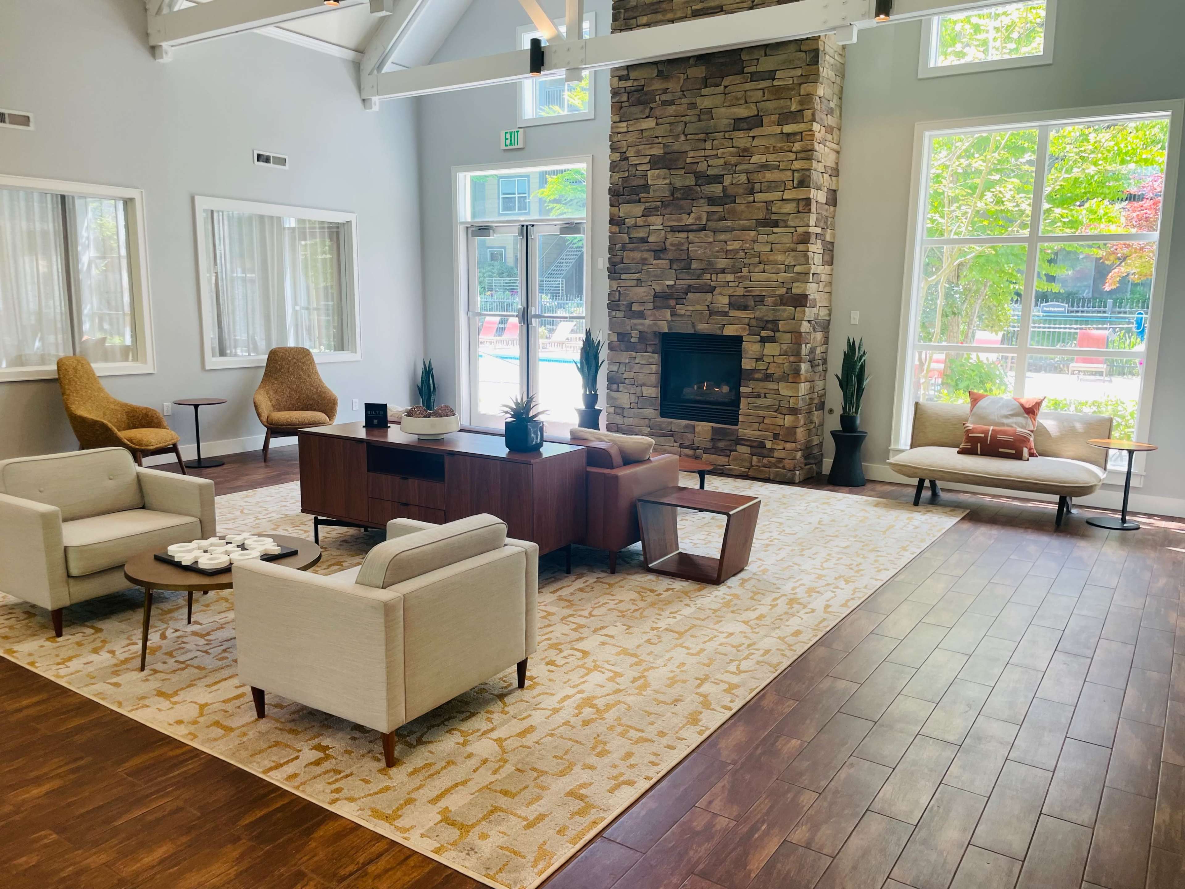A modern lounge area with a stone fireplace, comfortable seating, and large windows allowing natural light to fill the space.