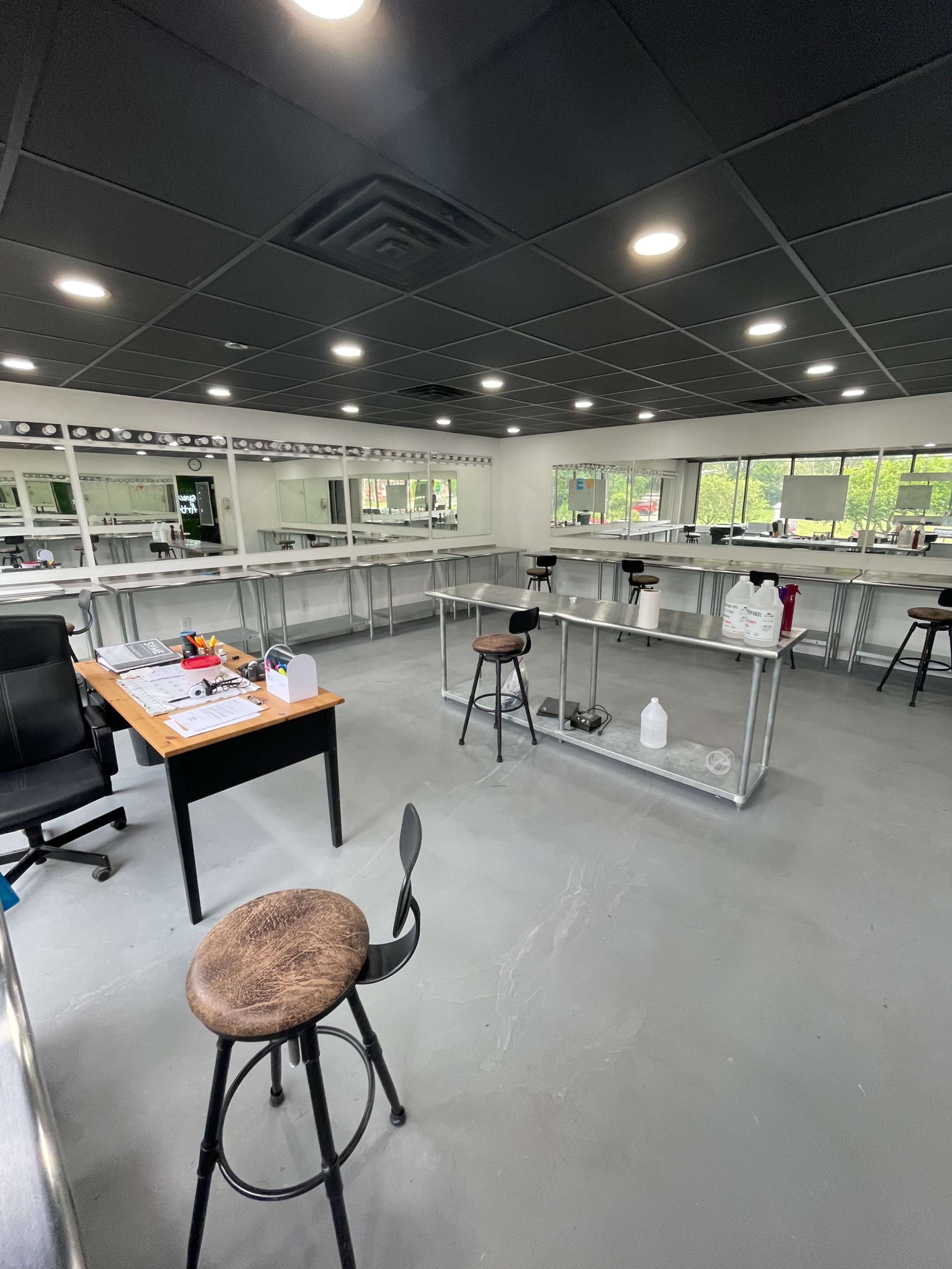 A spacious, well-lit lab or workspace featuring multiple tables and a desk with a chair.