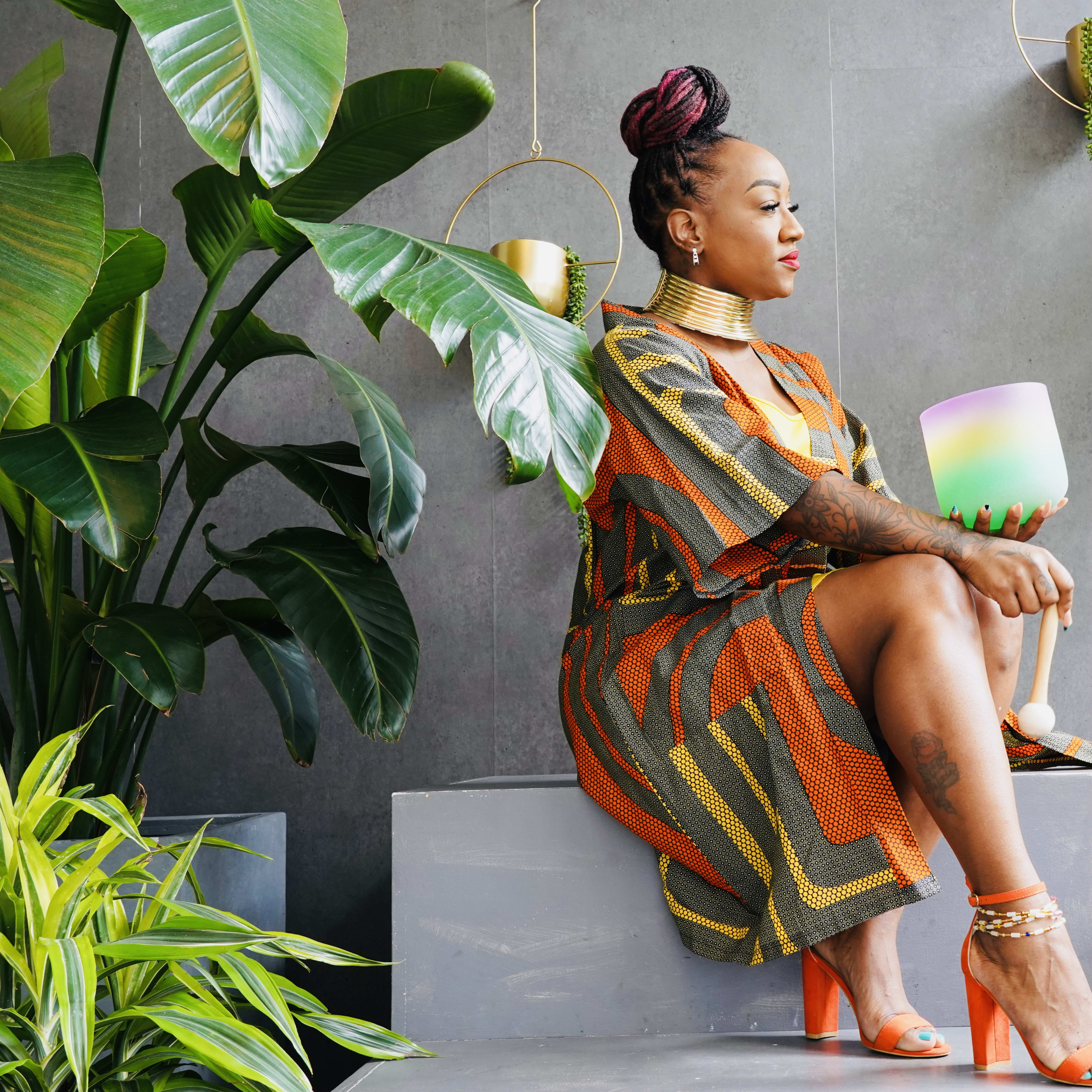 A fashion model posing on a bench surrounded by plants during a photo shoot.