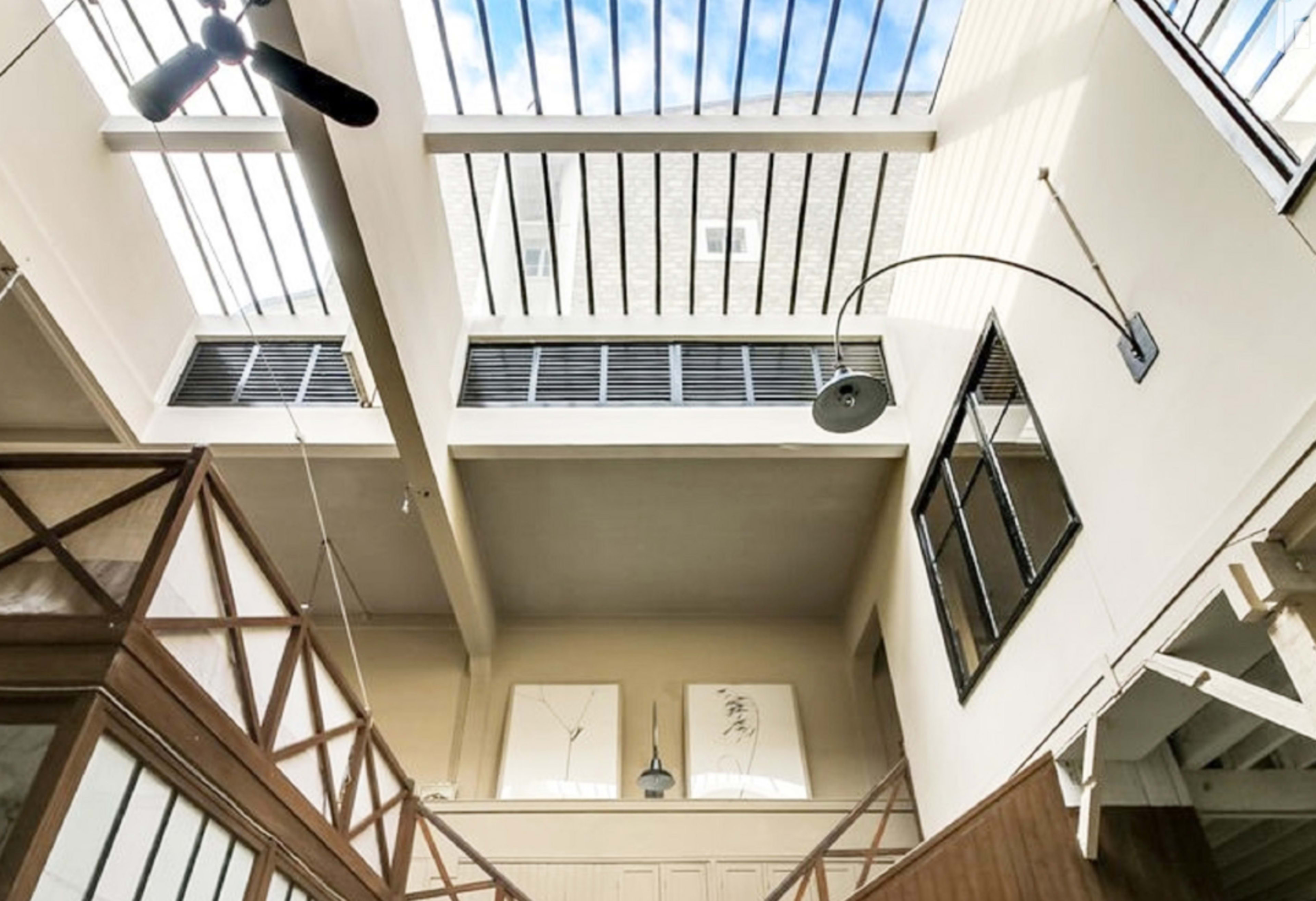 The interior of a spacious room with a high ceiling, featuring skylights and wooden architectural elements.