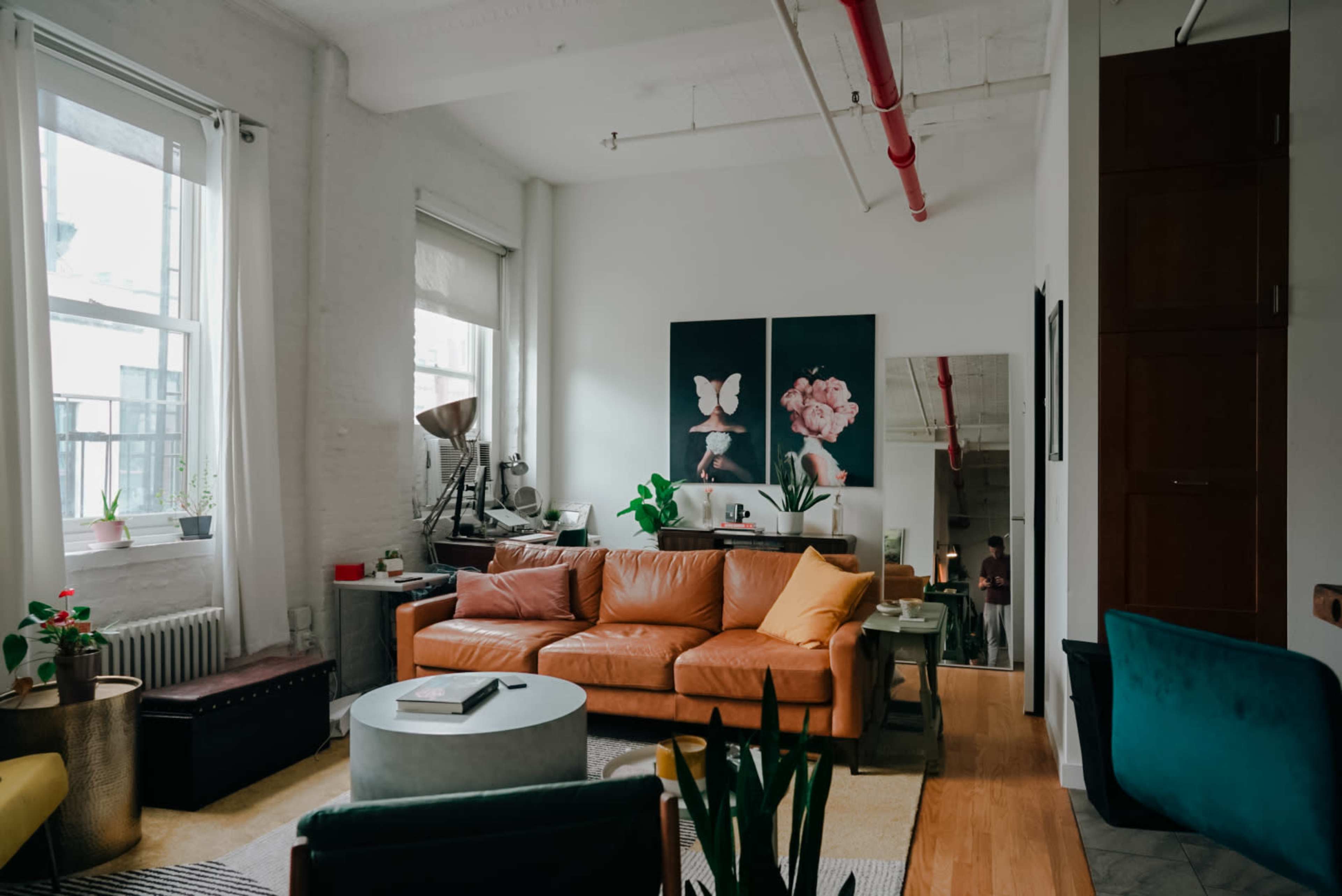 A well-lit living room featuring a brown leather sofa, a round coffee table, and large artwork on the wall.
