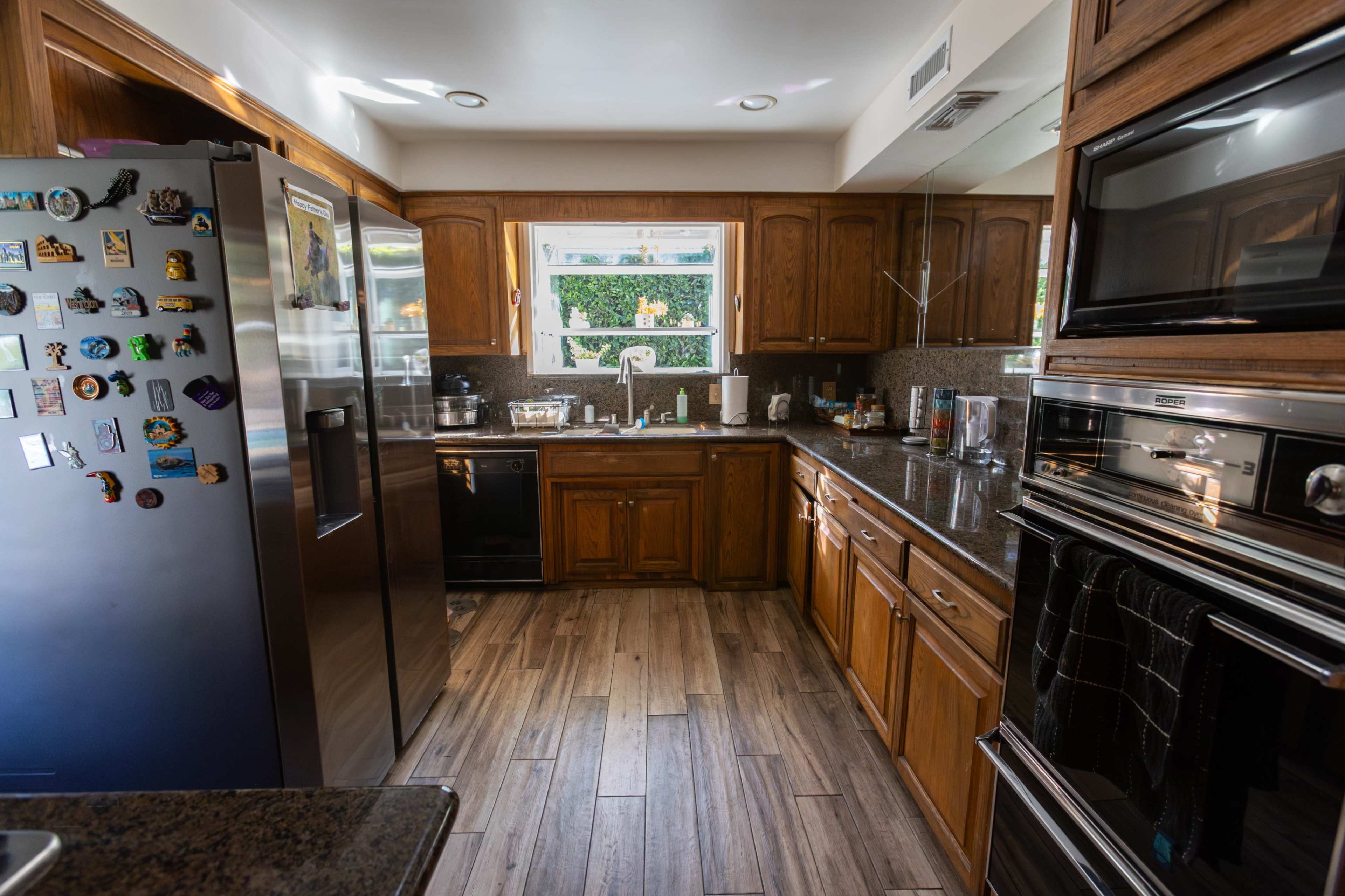 A kitchen featuring wooden cabinets, black appliances, and a window overlooking greenery.