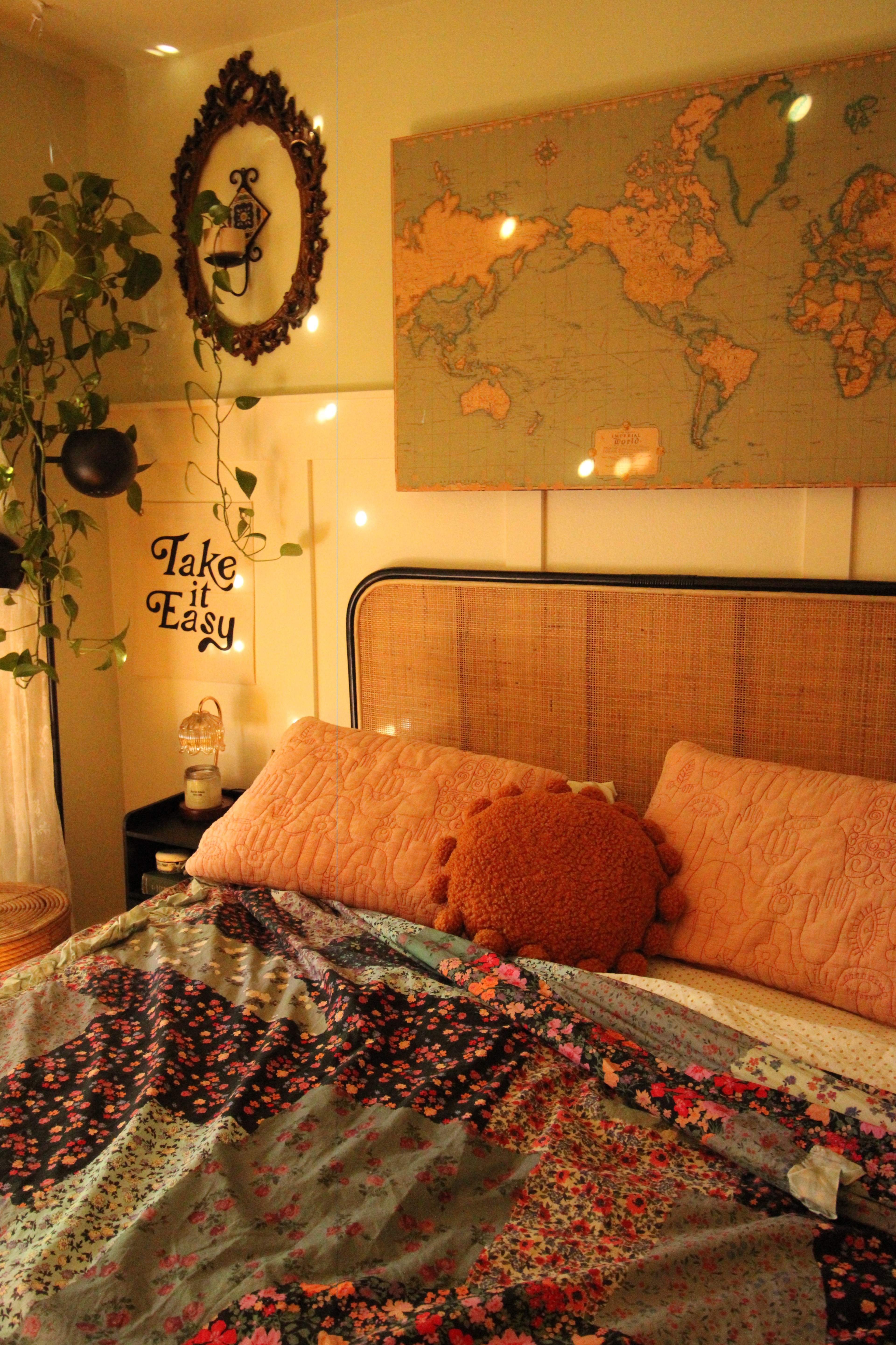 A cozy bedroom features a bed with floral bedding, a large map on the wall, and potted plants, creating a warm atmosphere.
