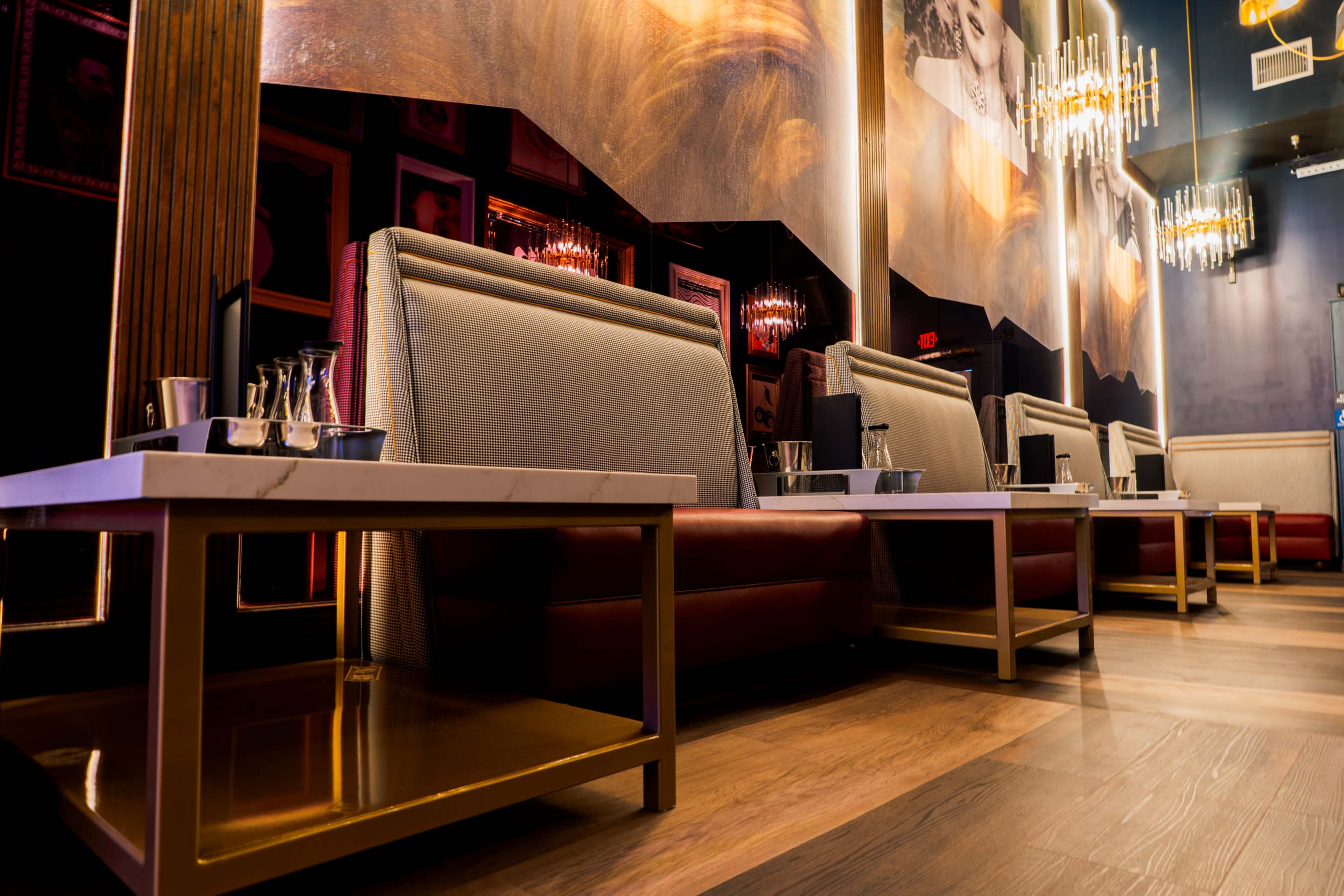 A stylish lounge area with upholstered seating, small tables, and wall decor featuring framed portraits.