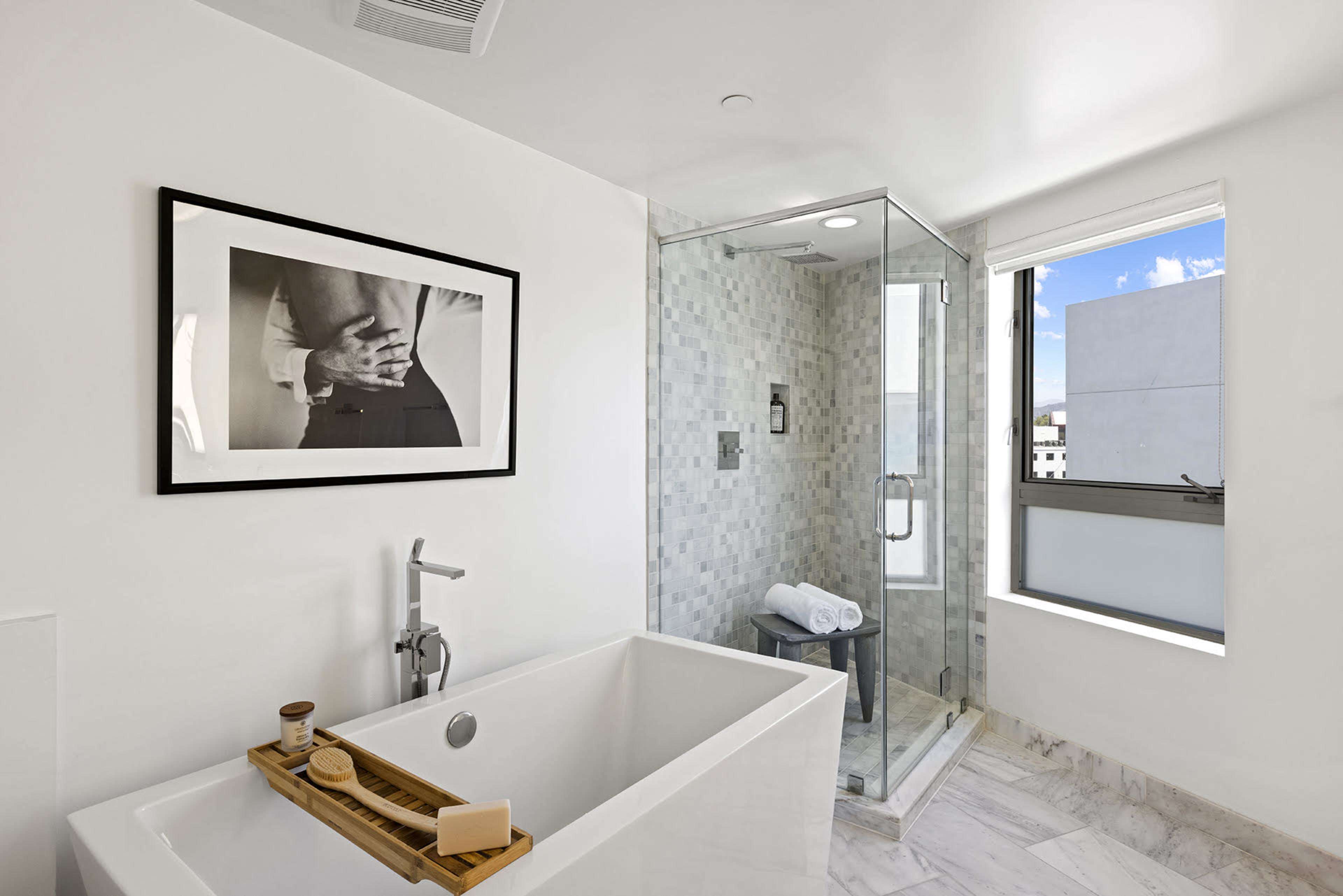 A modern bathroom featuring a freestanding bathtub and a glass shower enclosure with a tiled wall.