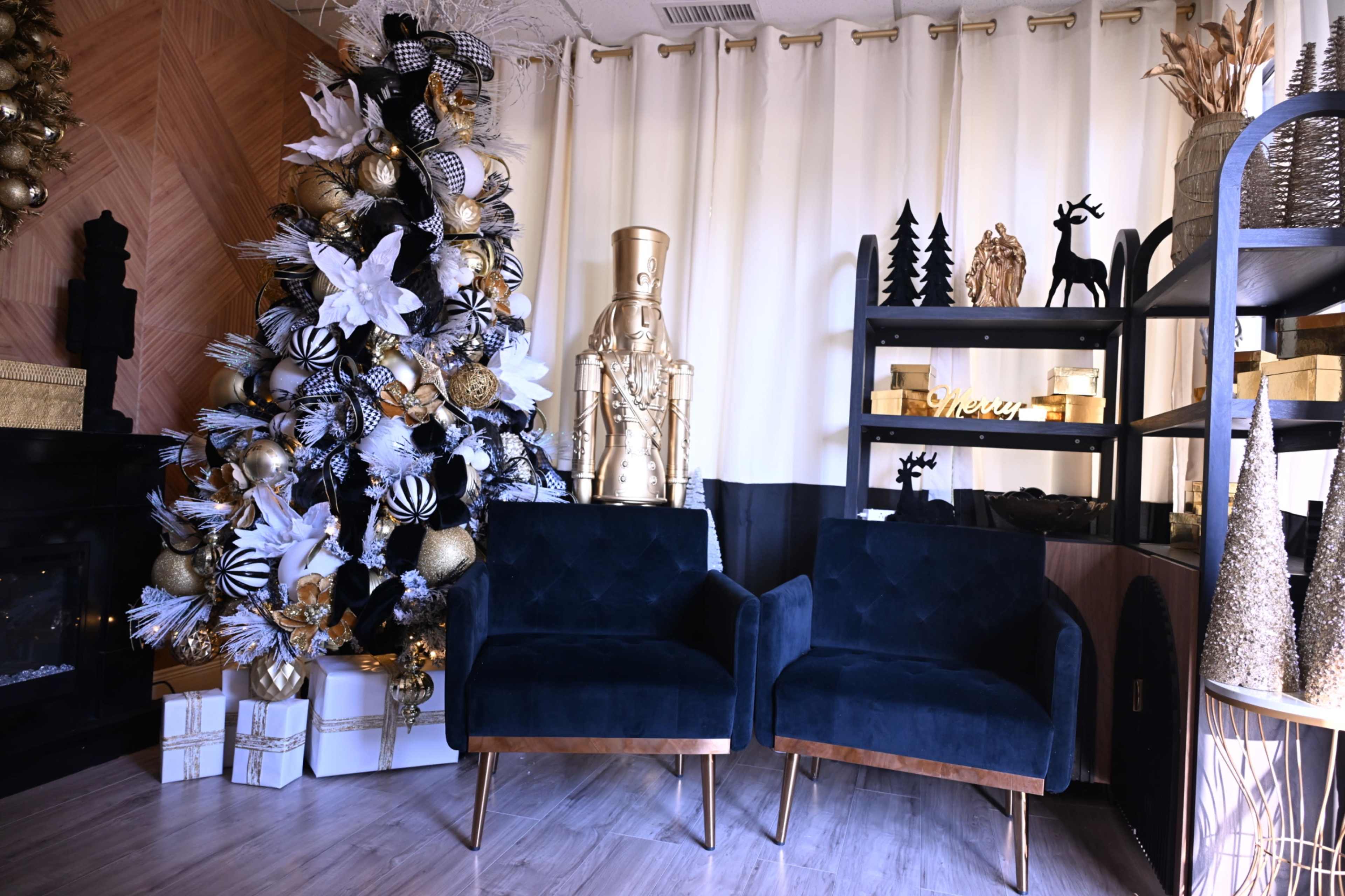 The image features a decorated Christmas tree with gold and black ornaments alongside two blue armchairs, a shelf with decorative items, and a golden nutcracker statue.