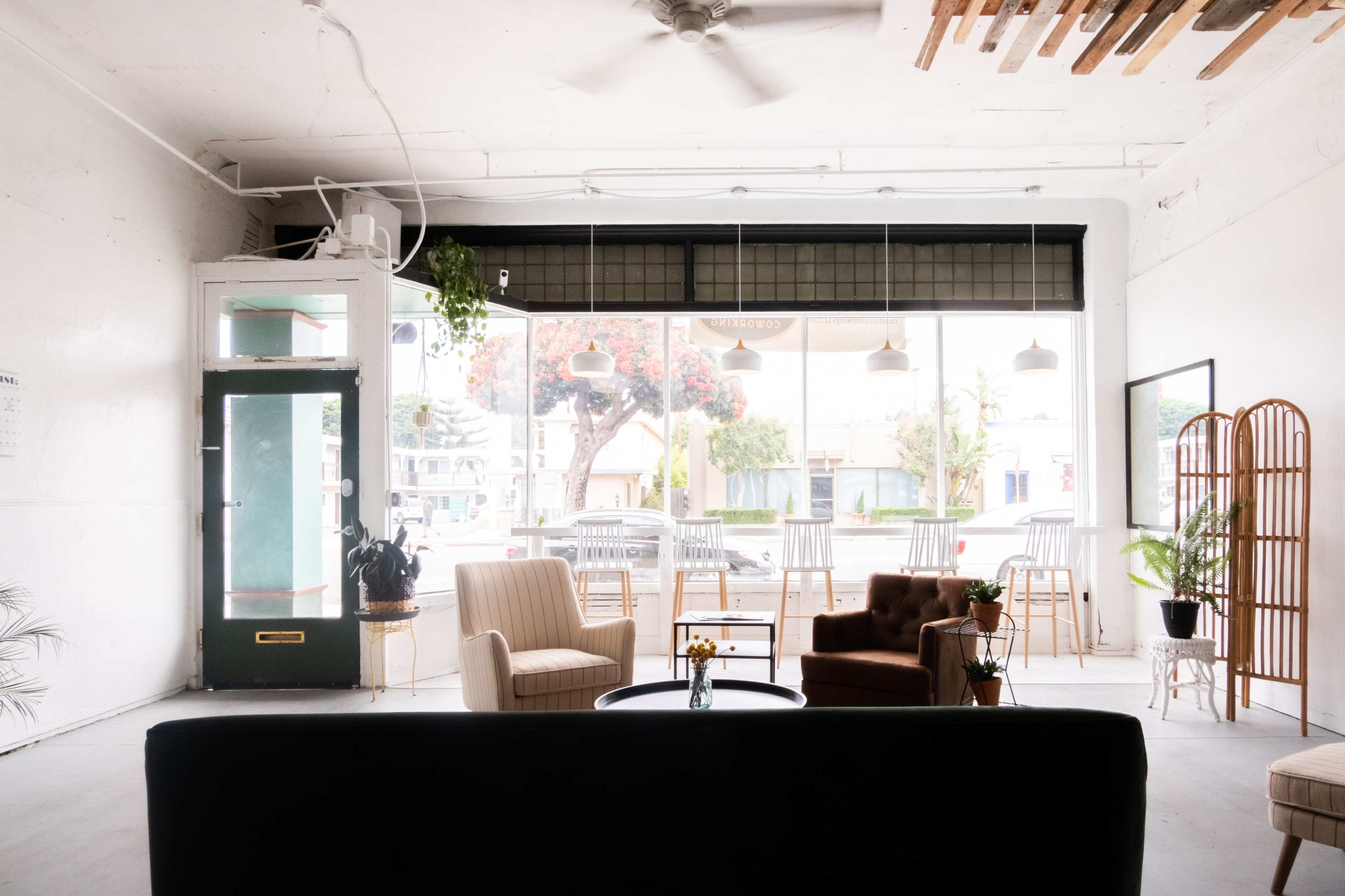 A spacious, well-lit café interior with seating arrangements and large windows facing an outdoor area.