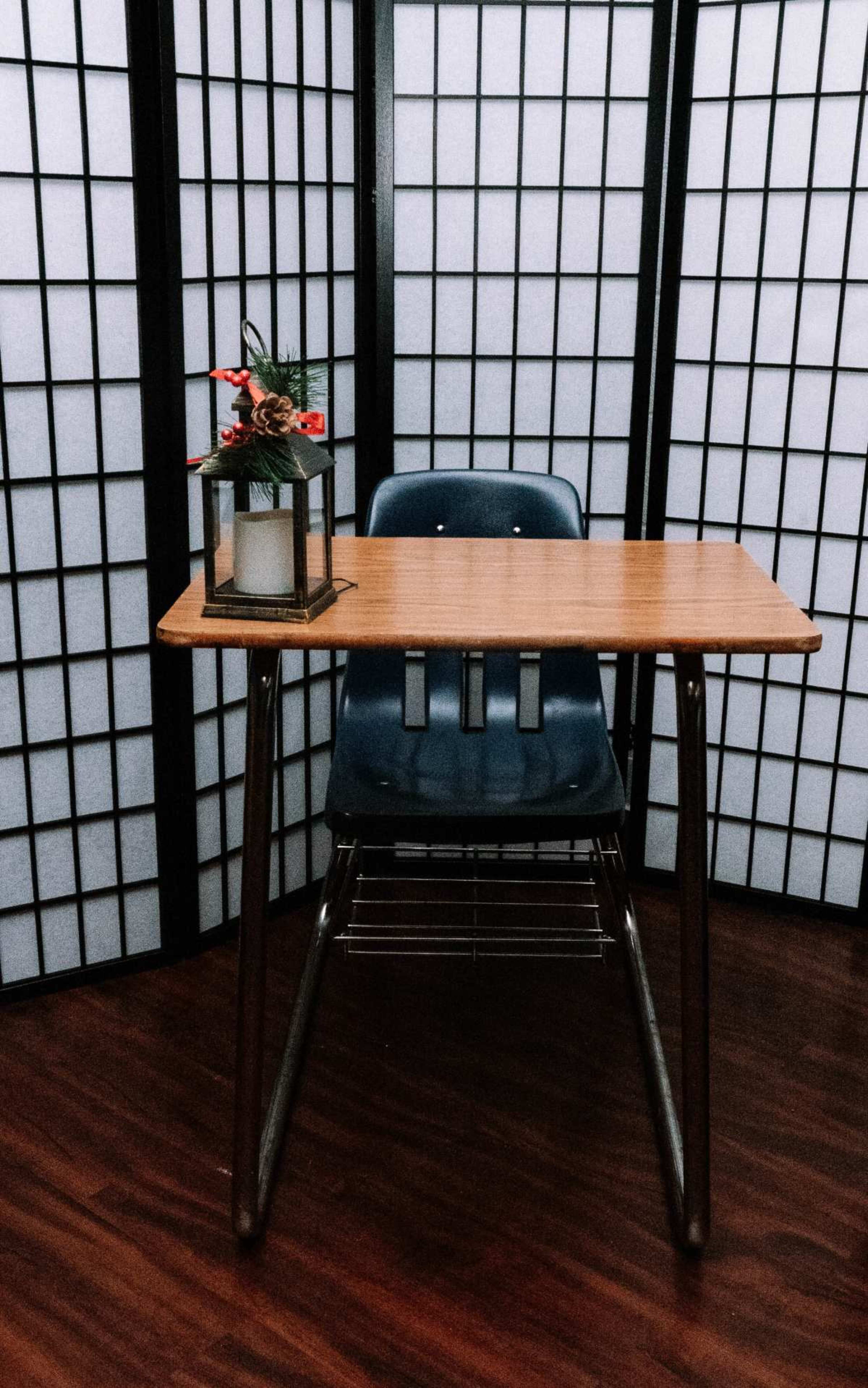 A wooden desk with a blue chair is set against a backdrop of white folding screens.