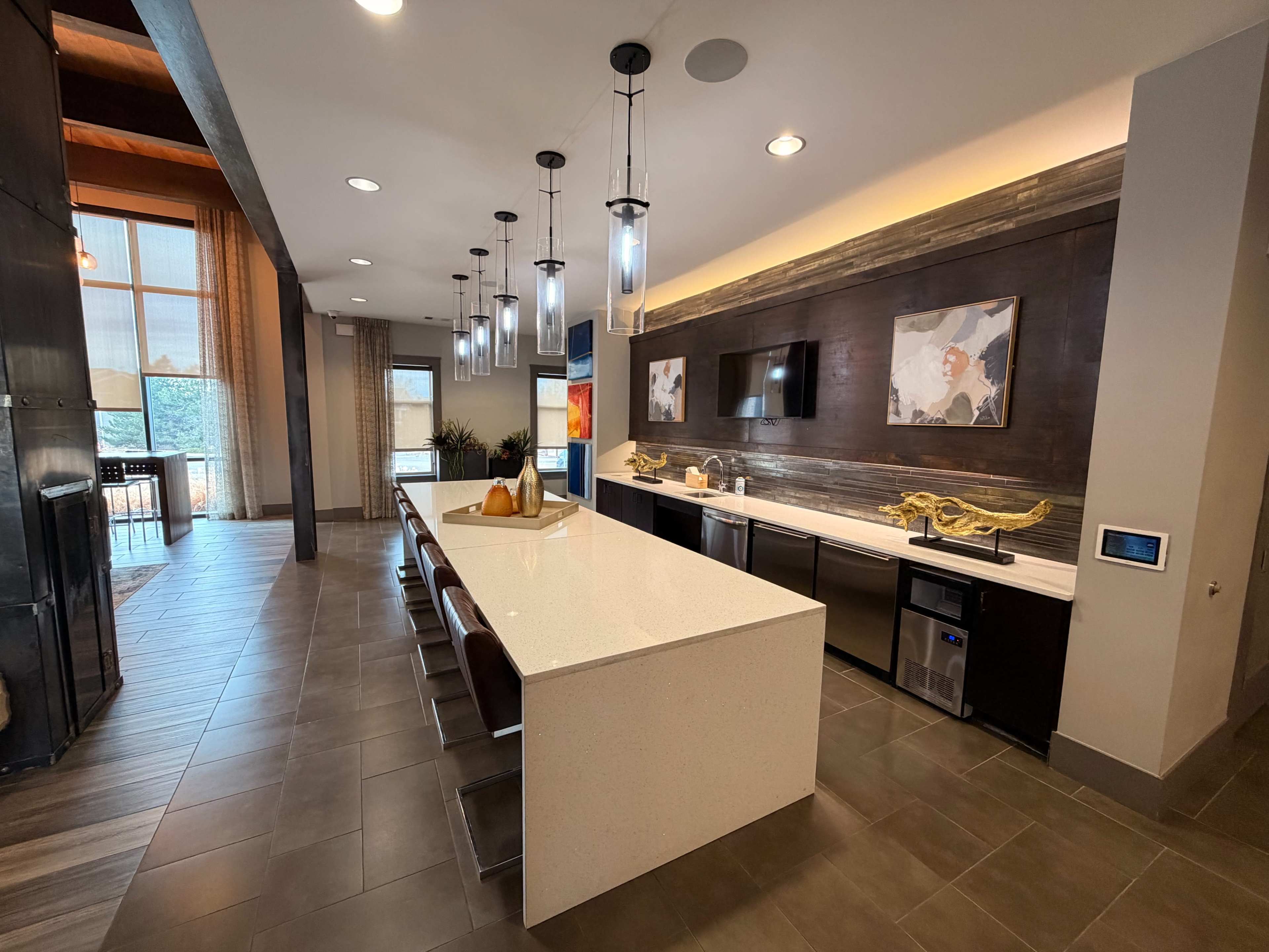 The image shows a modern kitchen with a large white island, dark cabinetry, pendant lighting, and a dining area visible in the background.