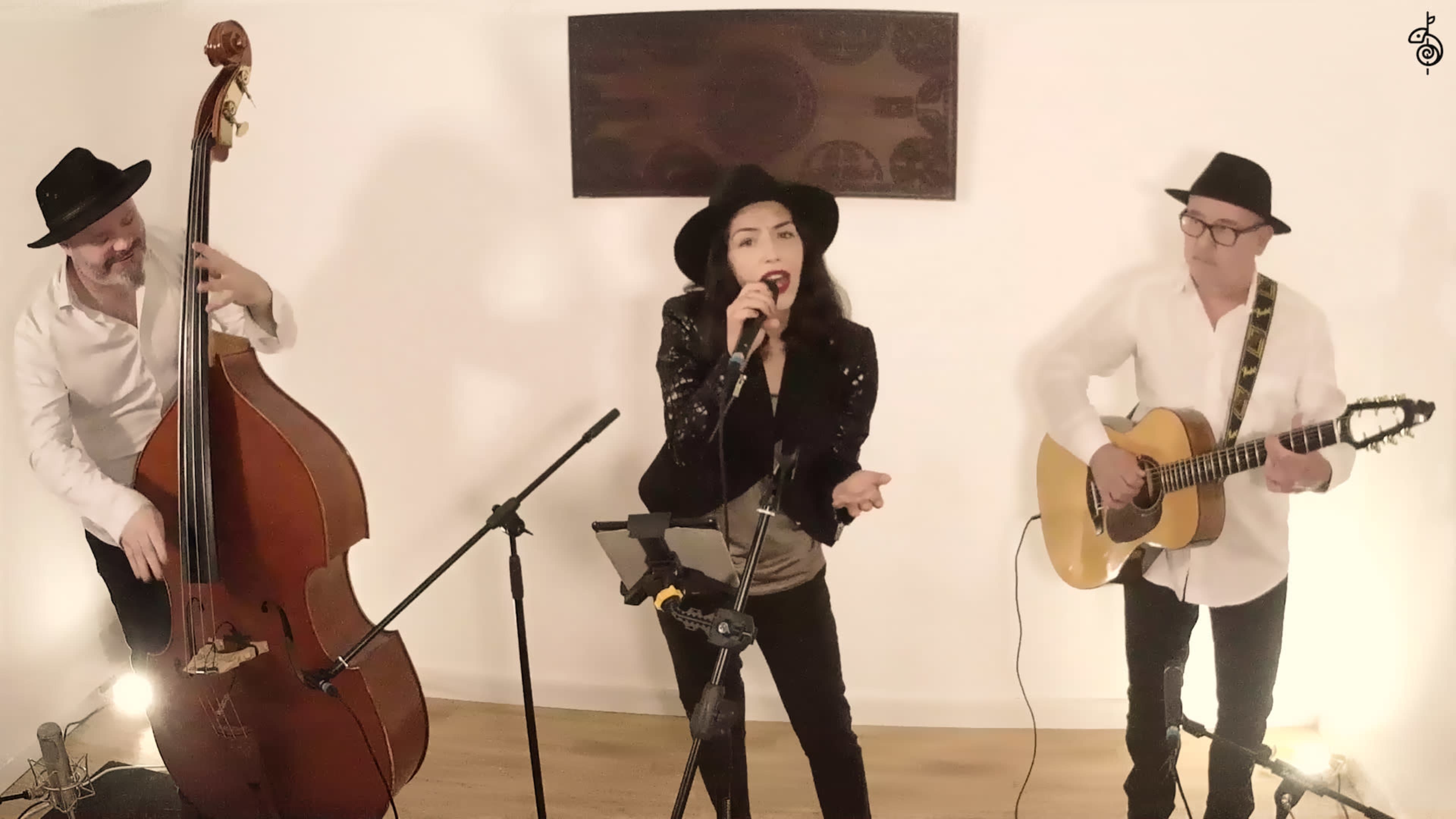 A trio of musicians performs in a well-lit room, featuring a singer with a microphone, a guitarist, and a double bassist.