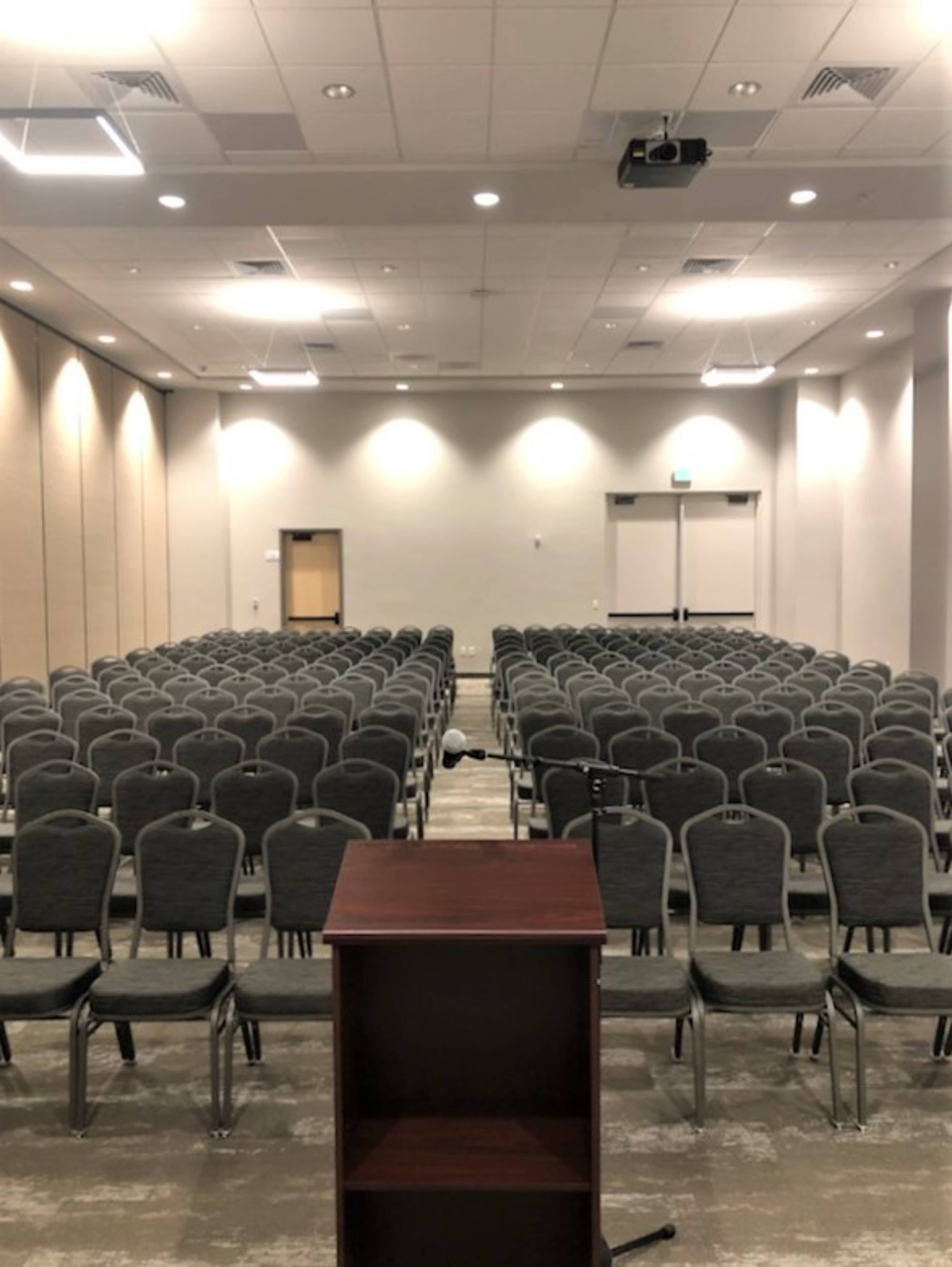A conference room filled with rows of empty chairs and a podium at the front.