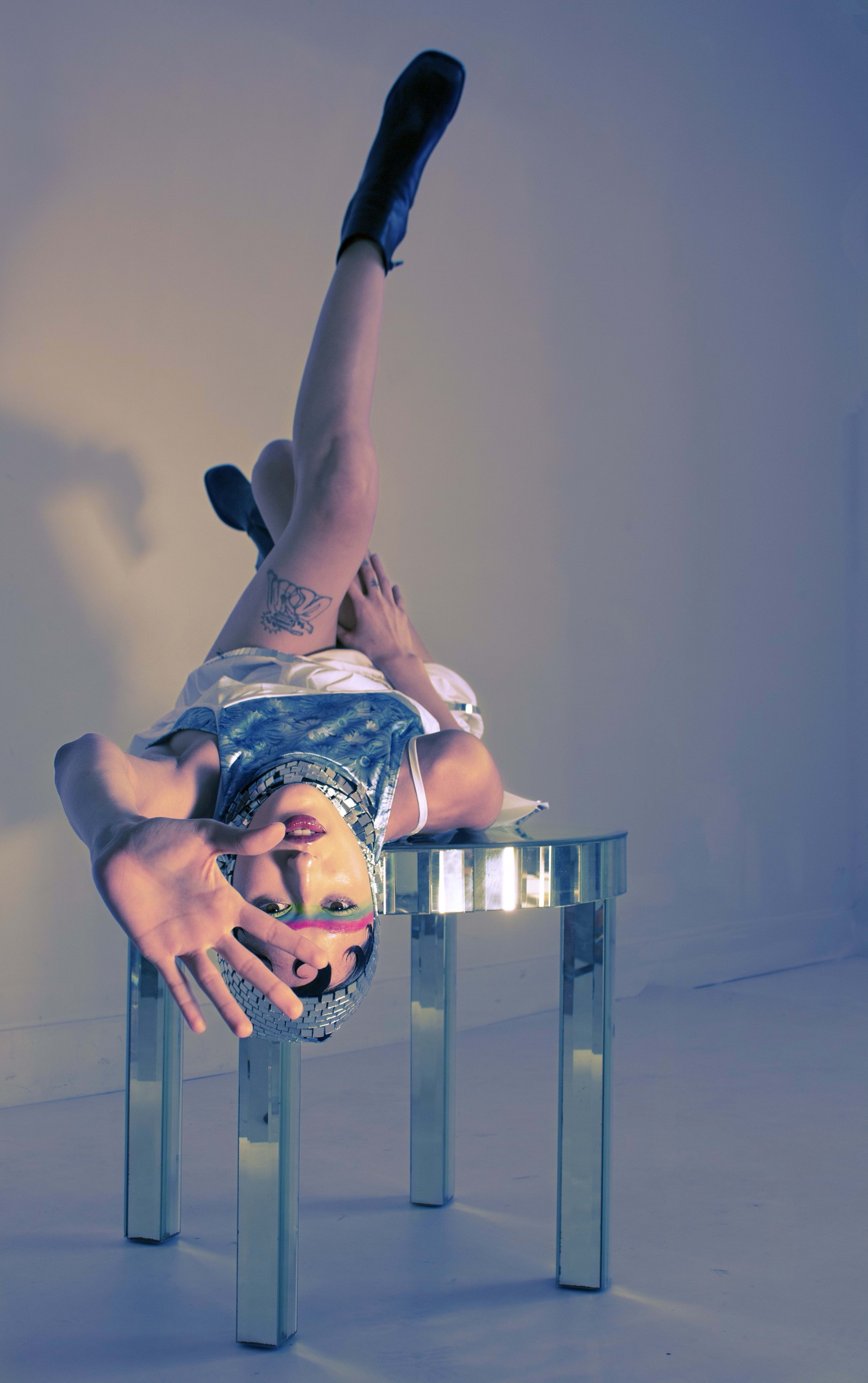 A person leaning back atop a table in a photo shoot.