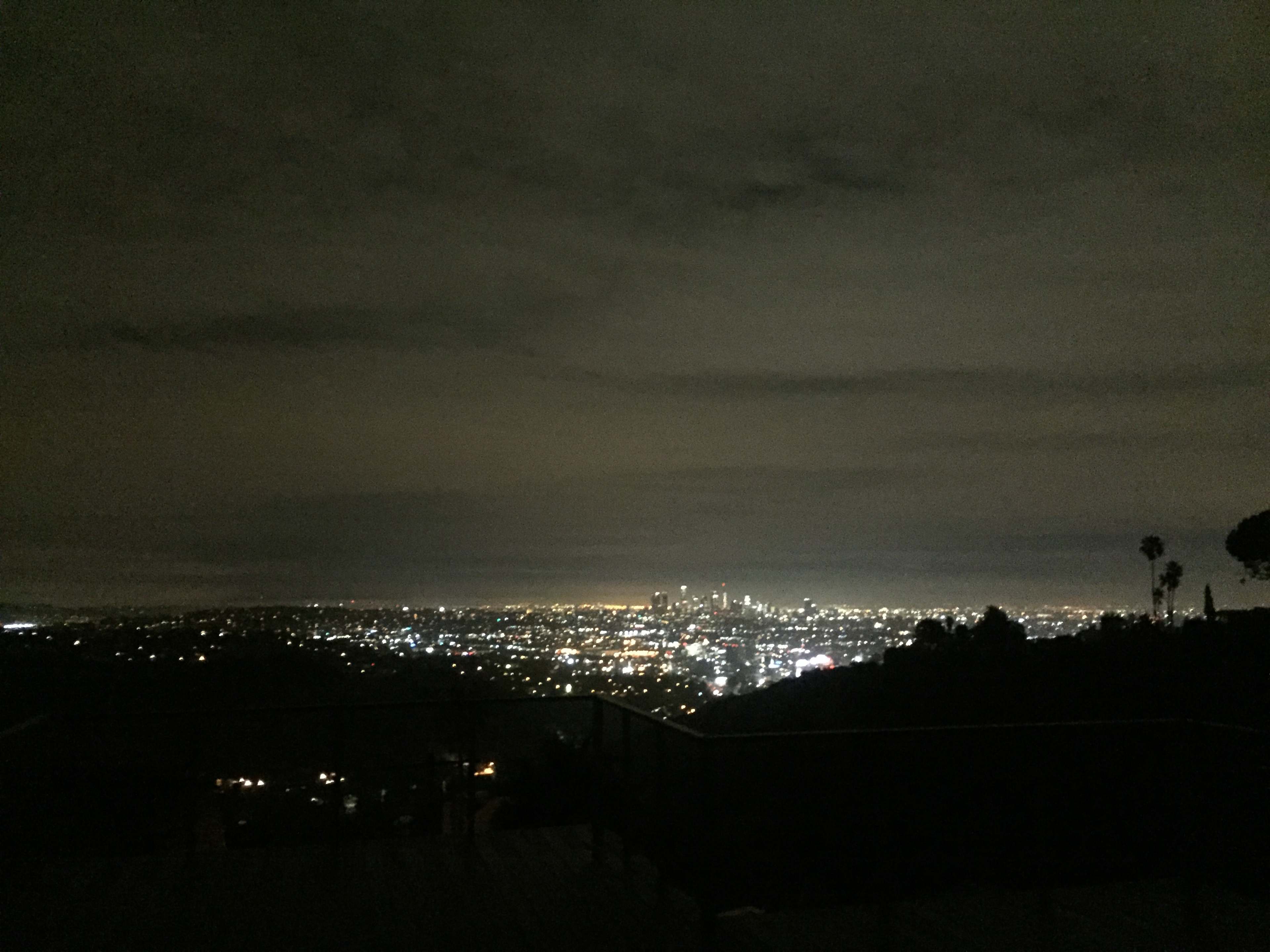 A city skyline is visible at night, illuminated by numerous lights against a cloudy sky.