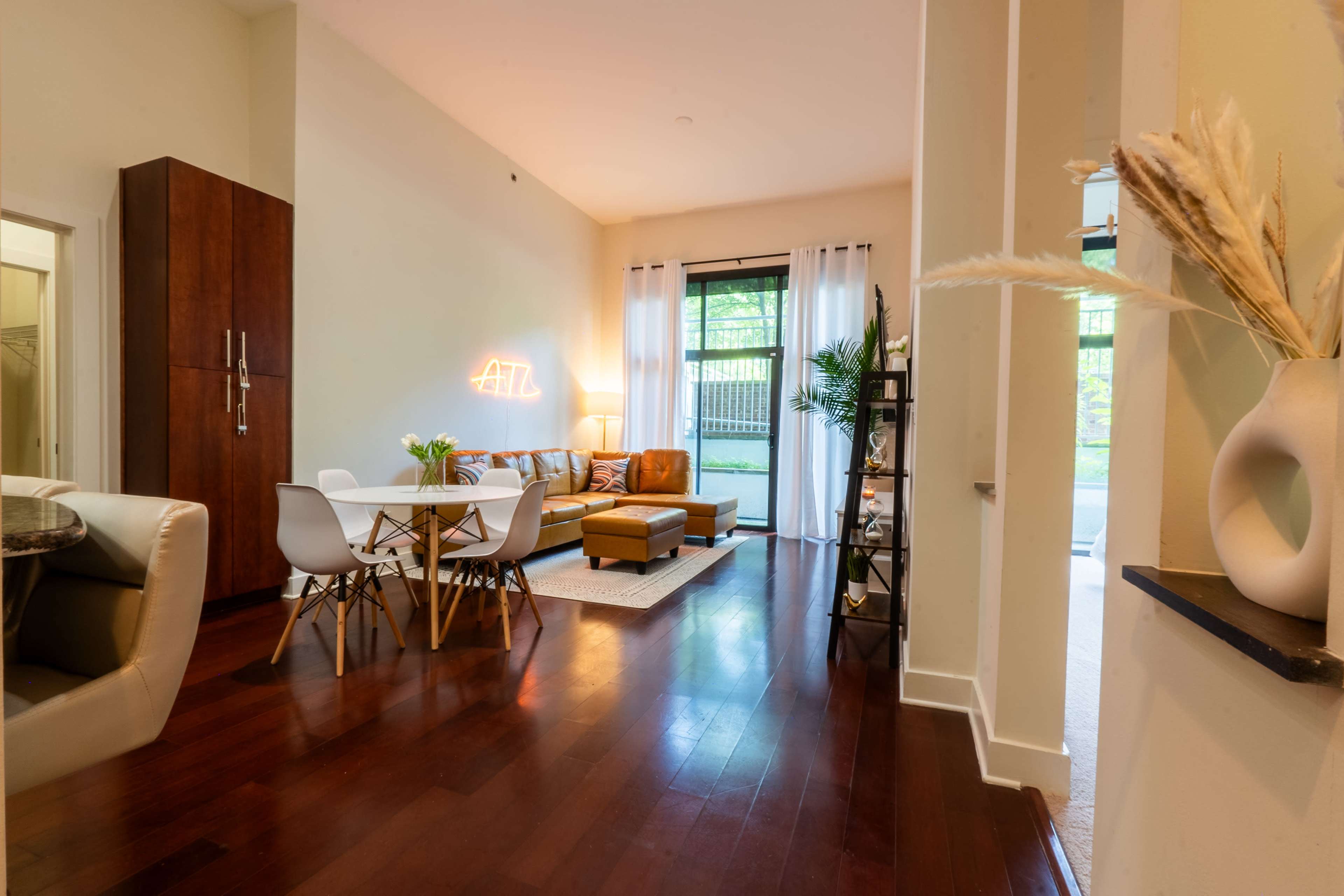 A modern living space with a dining area, a cozy sofa, and large windows allowing natural light.