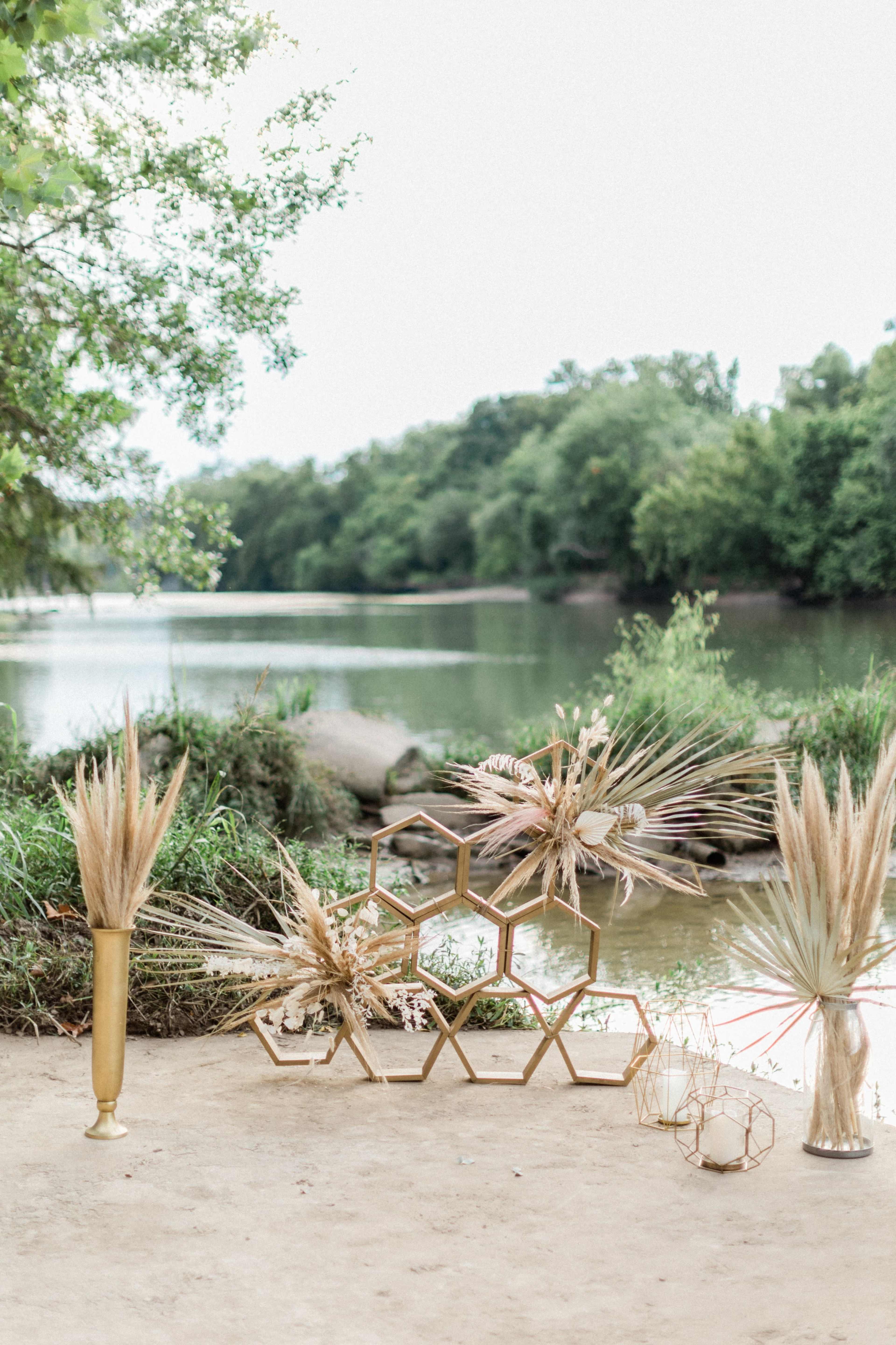 The scene features decorative arrangements of dried plants in geometric displays along a riverside.