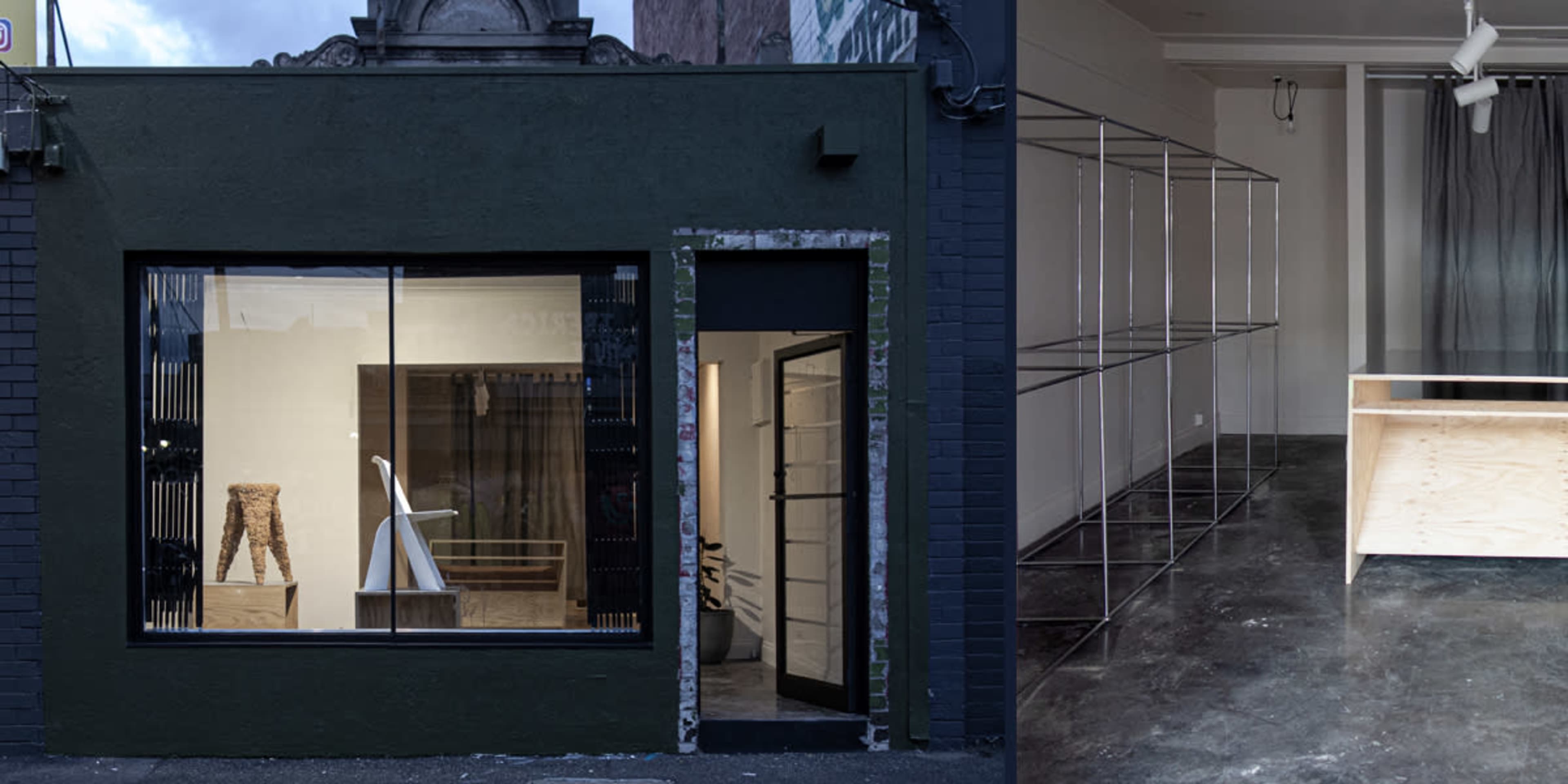 The exterior of a modern dark green building with large windows displaying minimalist furniture and an interior featuring a clean, open space with a wooden table and metal shelving.