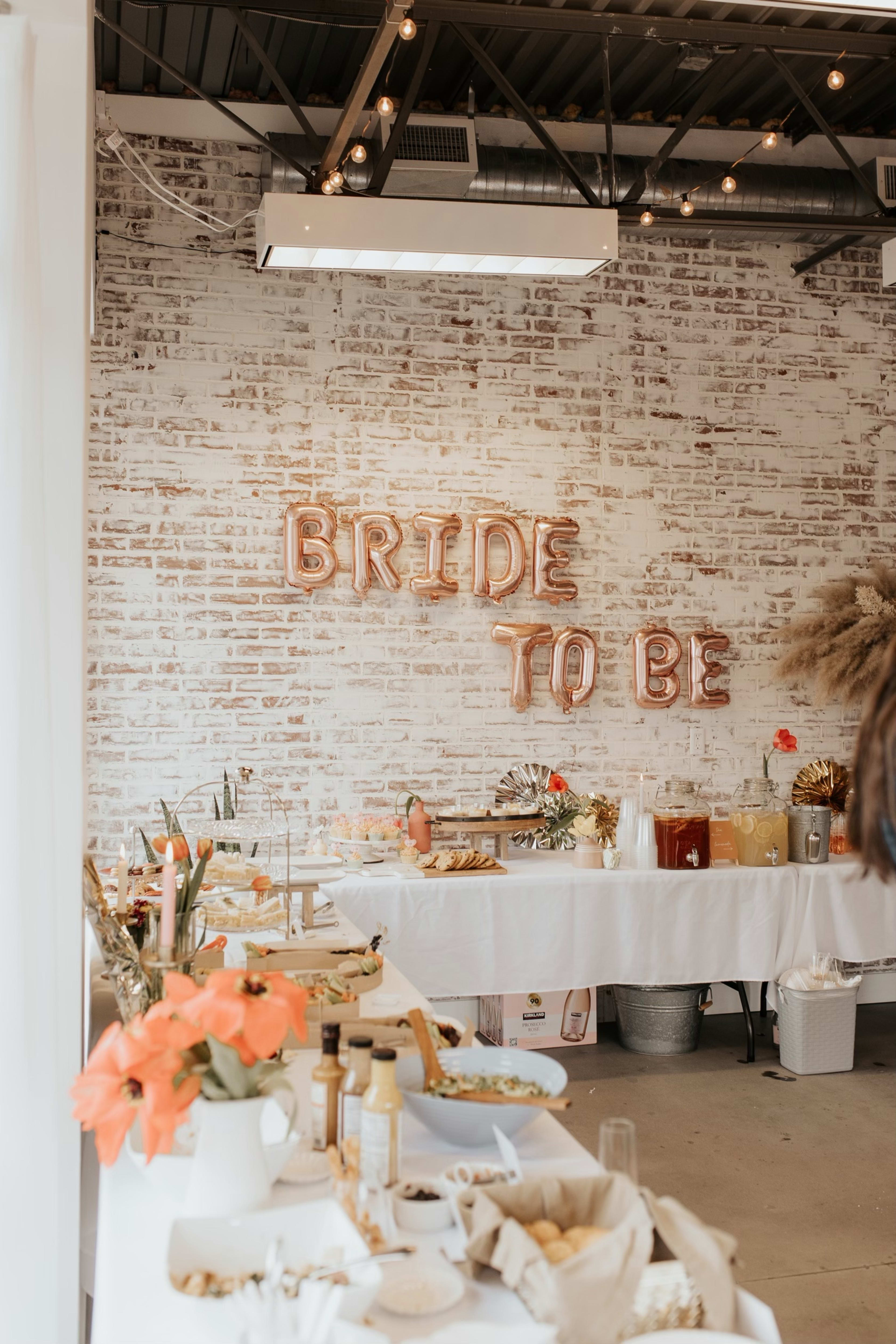 Ein Schild „Bride to be“ im Landhausstil an einer Ziegelwand.