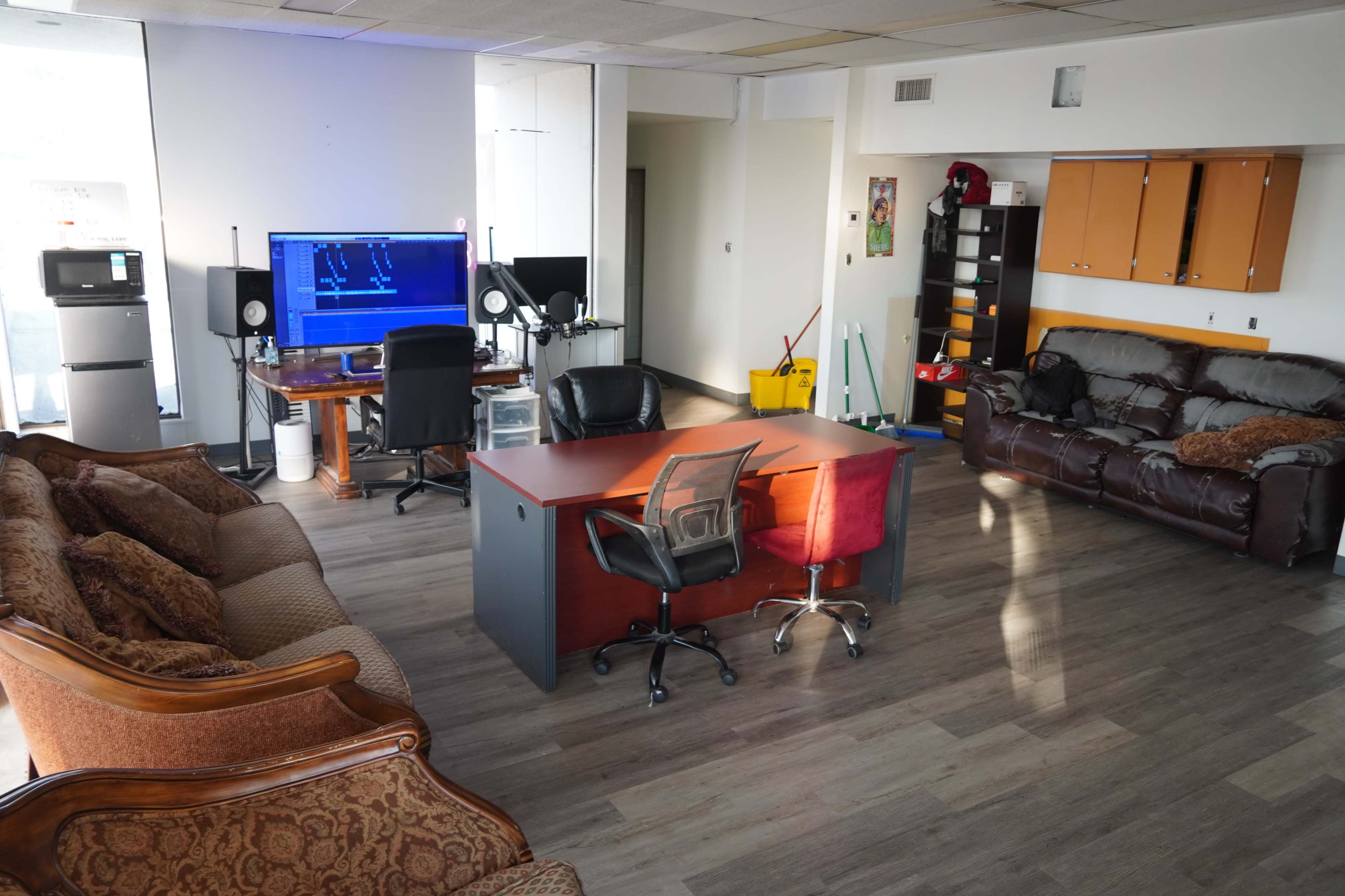 The image shows an office space with a desk and chairs in the center, two couches on opposite sides, and various office equipment including a computer and a printer.