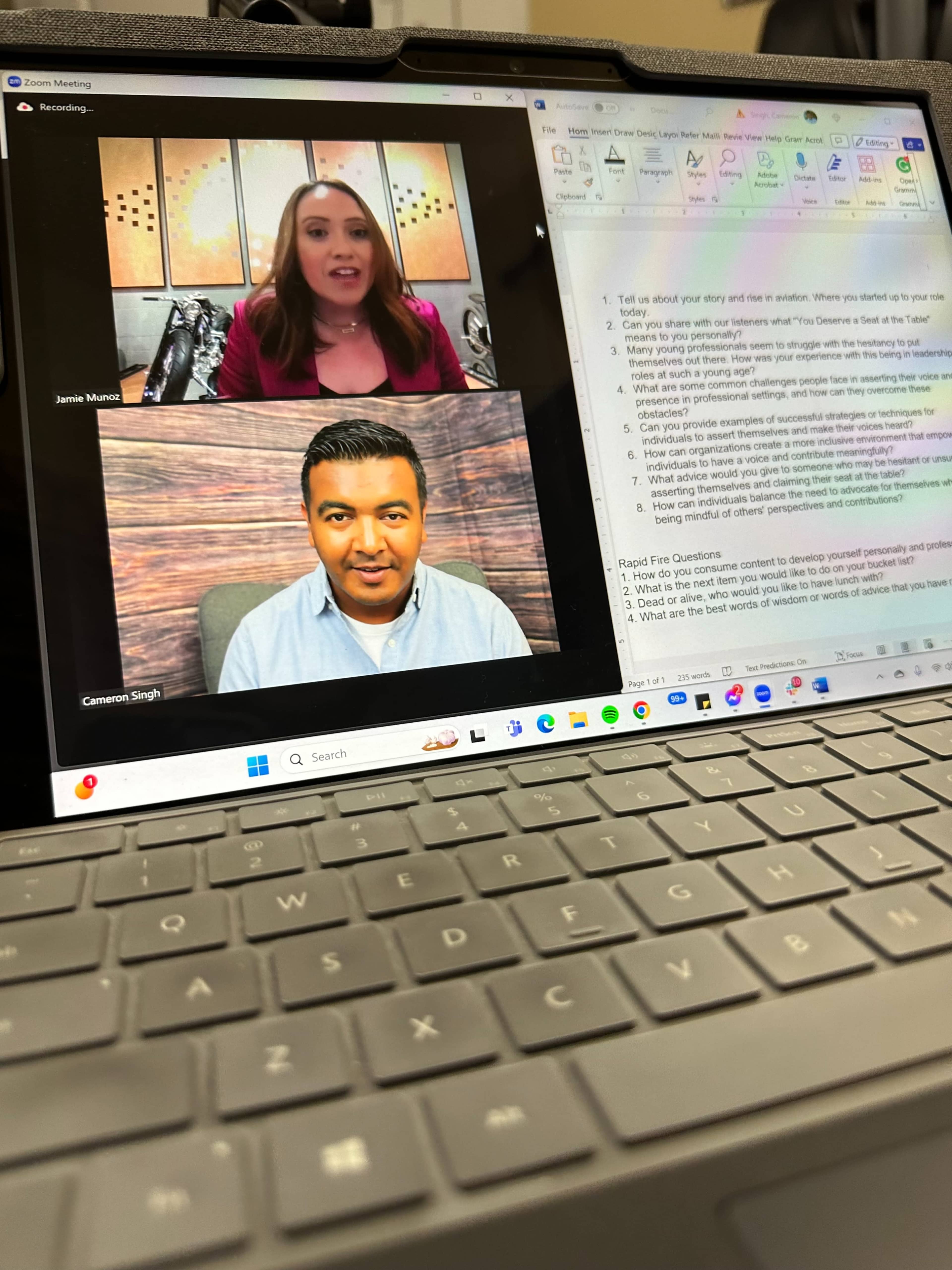 A video call on a laptop screen, featuring two individuals, one speaking in an upper window and the other listening in a lower window.