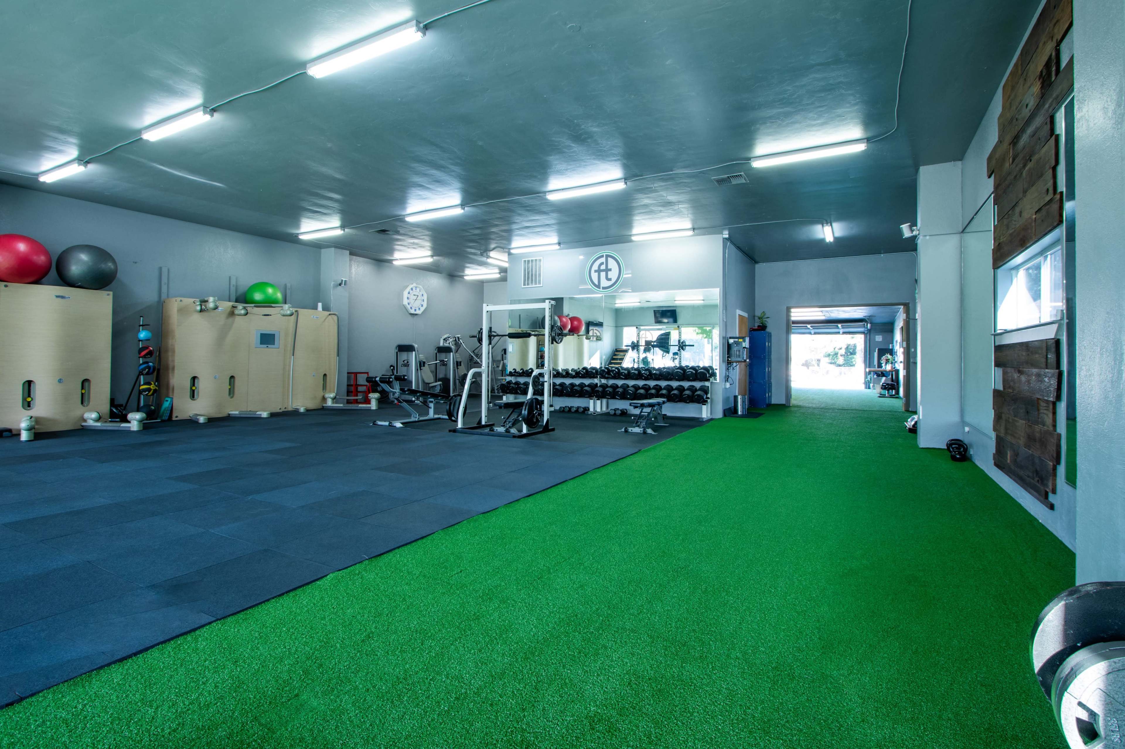 A spacious gym equipped with workout machines, free weights, and a grassy area for exercise.