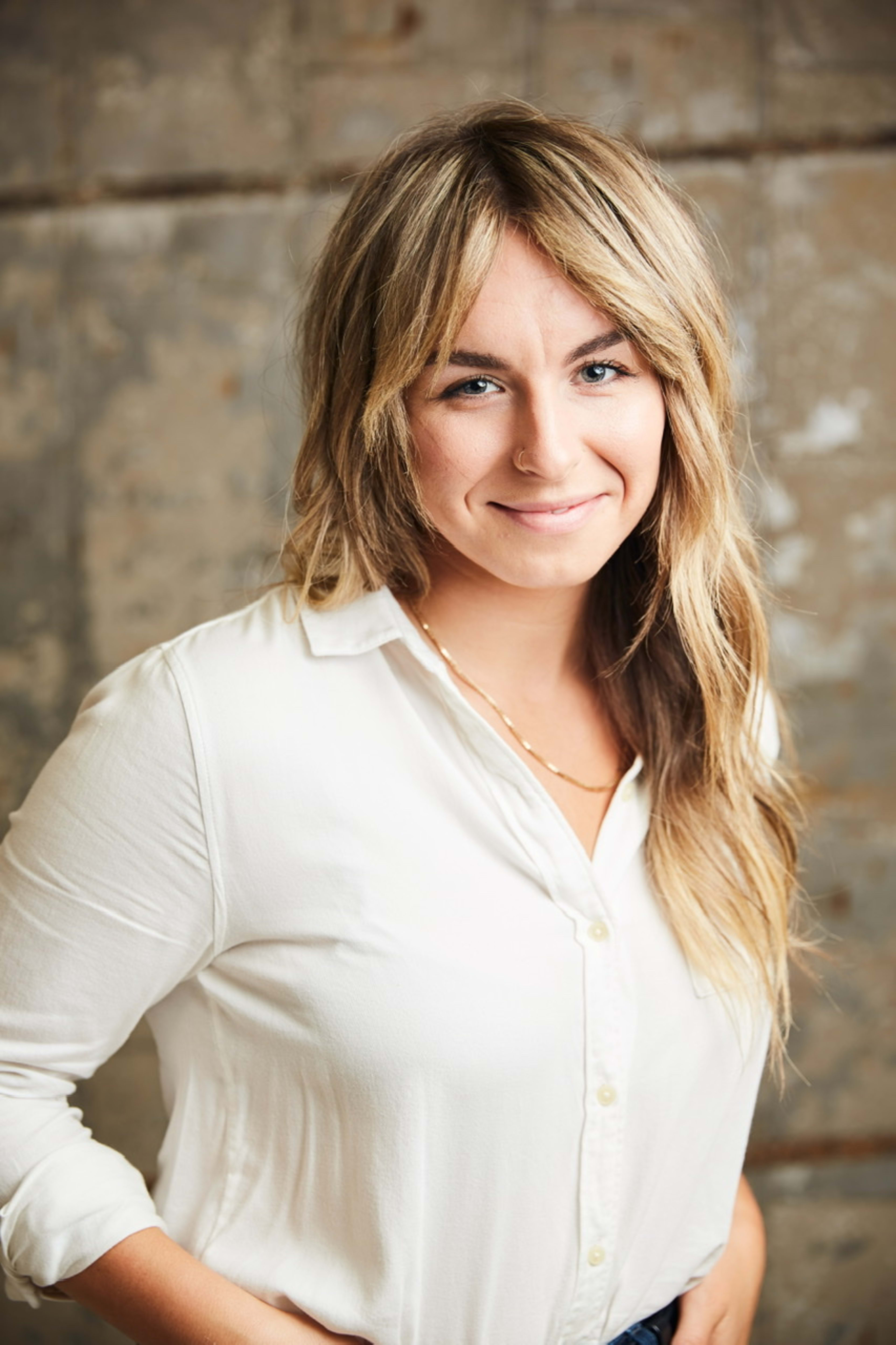 Une femme vêtue d’une chemise blanche minimaliste posant pour un portrait.