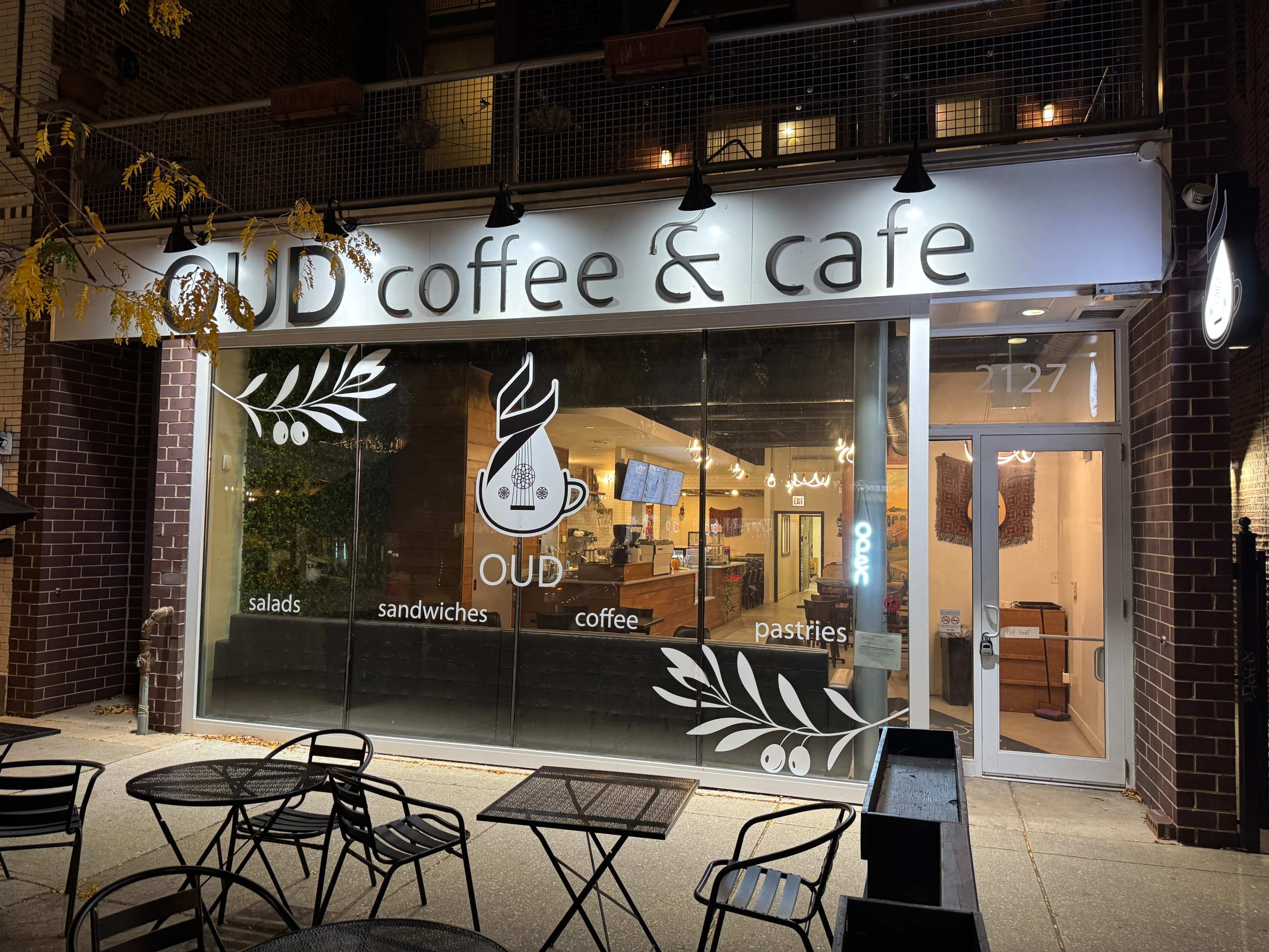 A cafe named "OUD coffee & cafe" displays its offerings, including salads, sandwiches, coffee, and pastries, in a lit storefront.