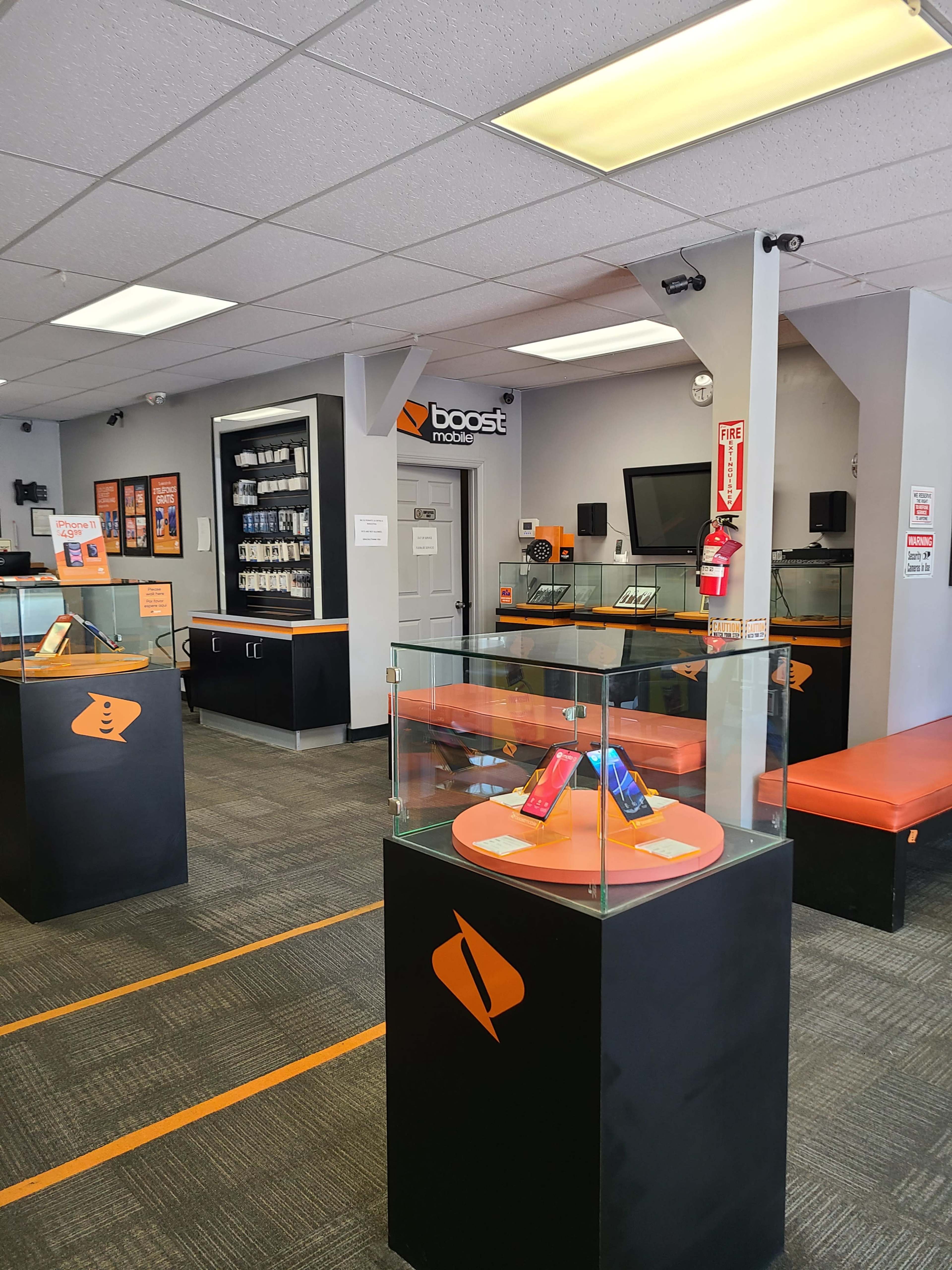 The interior of a Boost Mobile store, featuring display cases with mobile phones and service information, alongside seating areas and various merchandise on the walls.