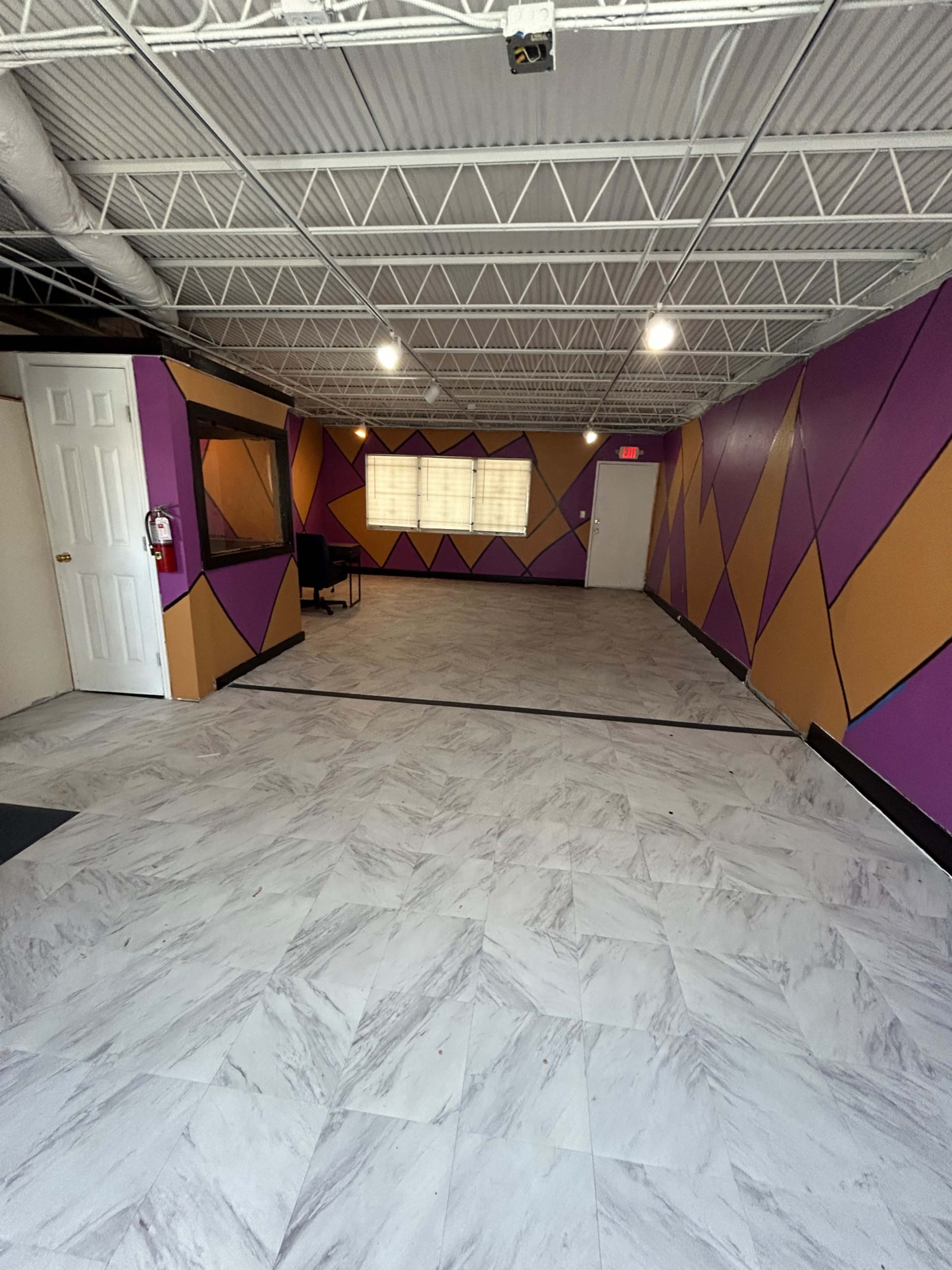 An empty room with patterned purple, gold, and beige walls and a tiled floor.