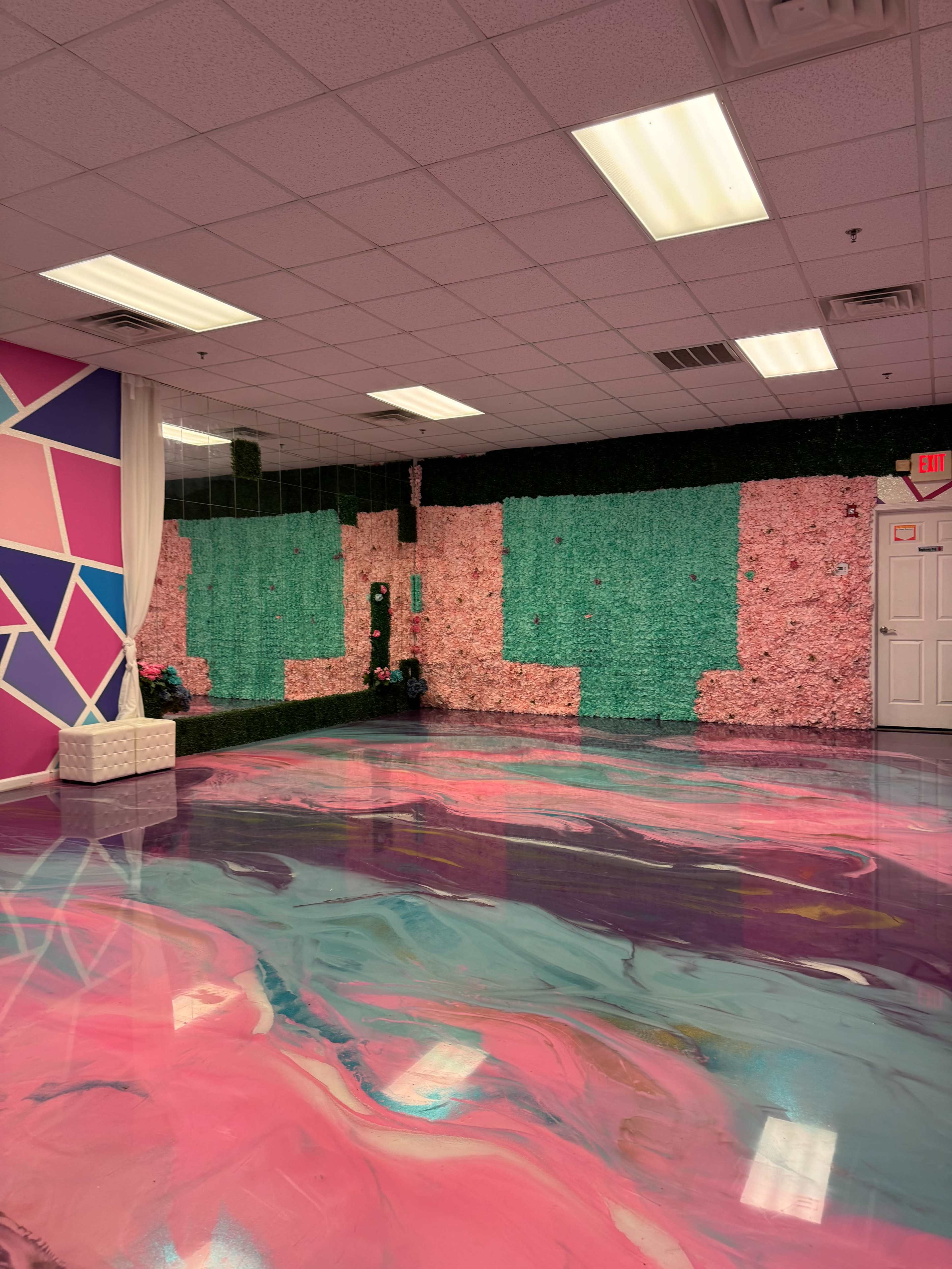 A room with colorful walls featuring pink, green, and geometric patterns, alongside a shiny, marbled floor in shades of pink and purple.
