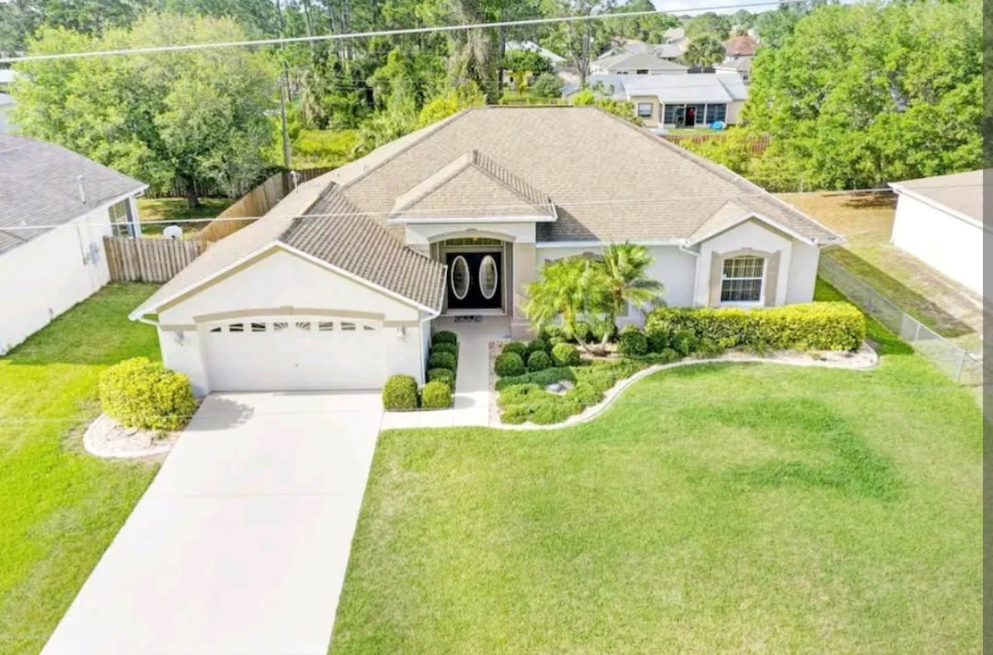 Aerial view of a single-story house with a manicured lawn and a driveway leading to a double garage.