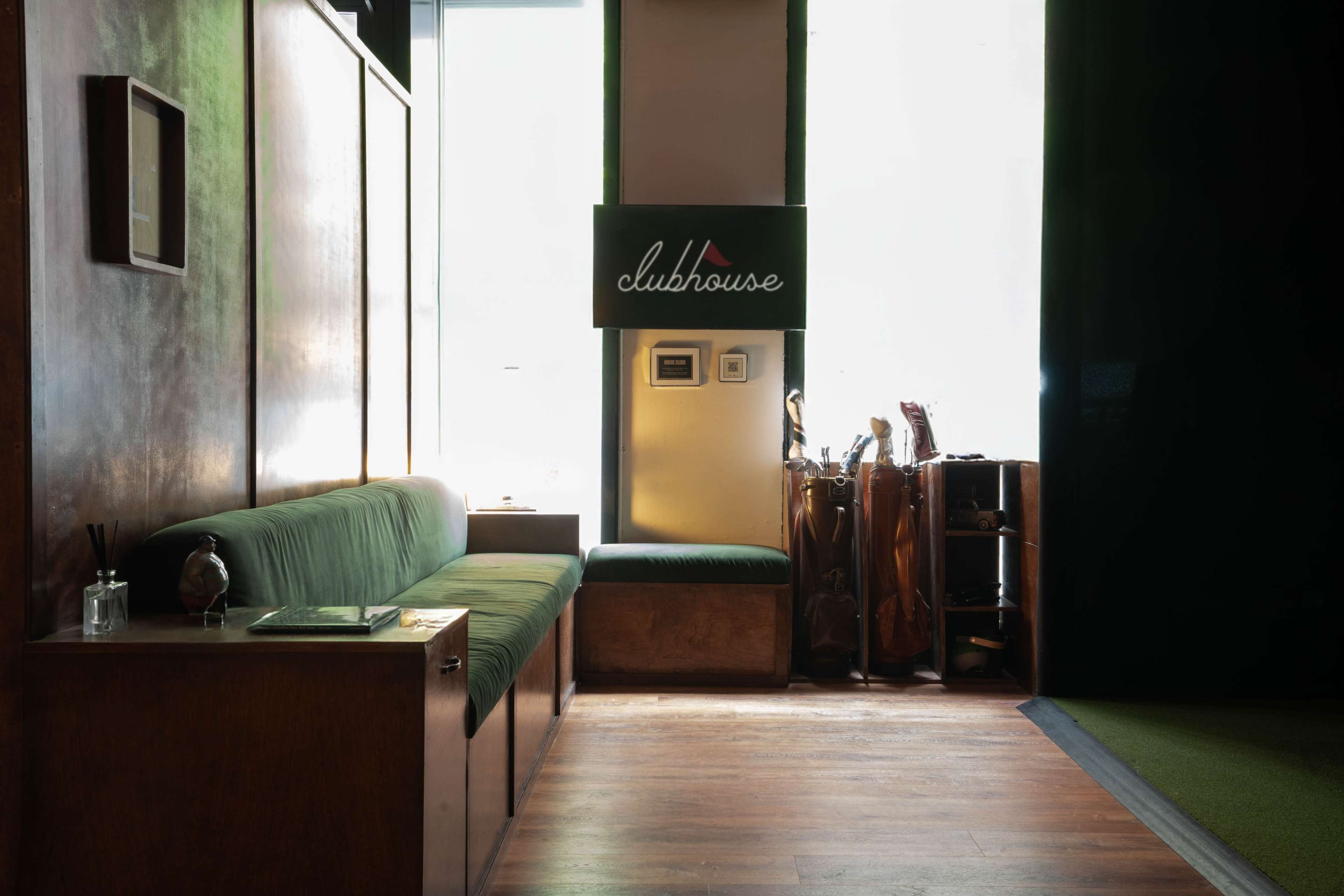 The image shows a cozy interior space with a green couch, a sign reading "clubhouse," and wooden paneling.