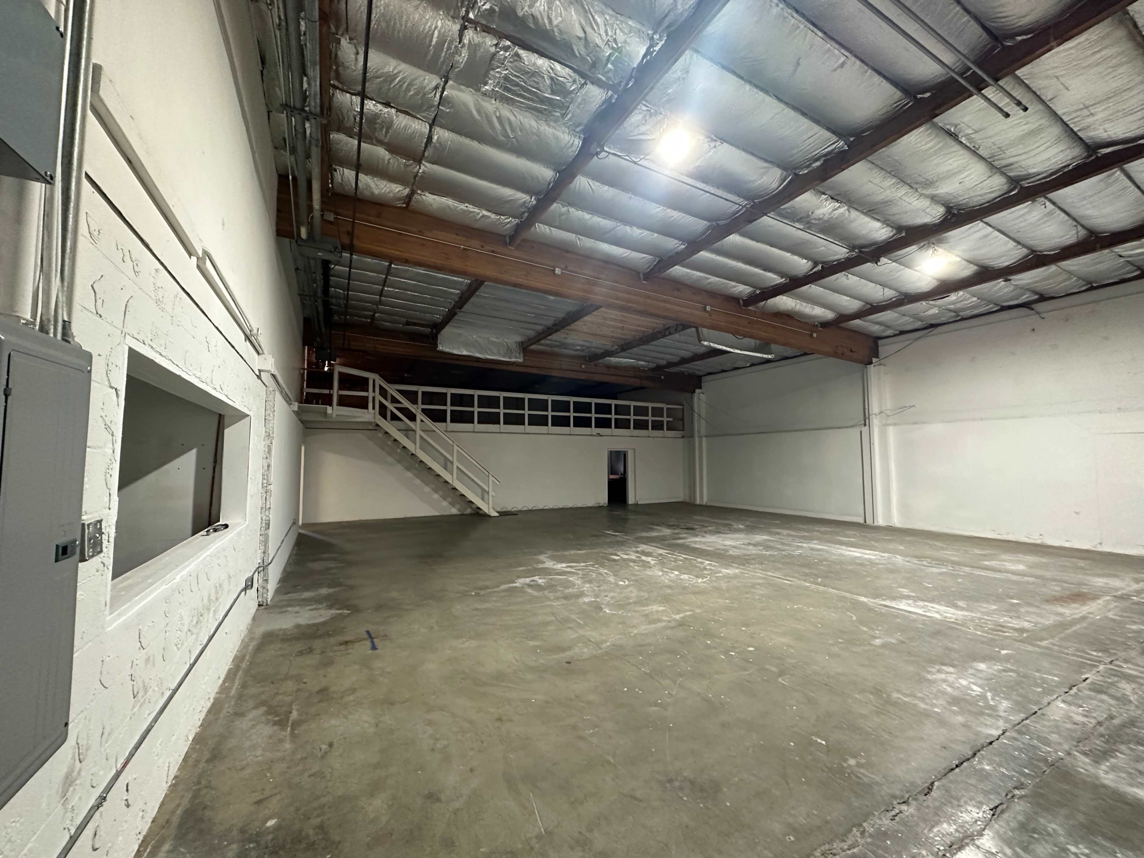 A spacious, empty warehouse with a polished concrete floor and exposed beams in the ceiling.