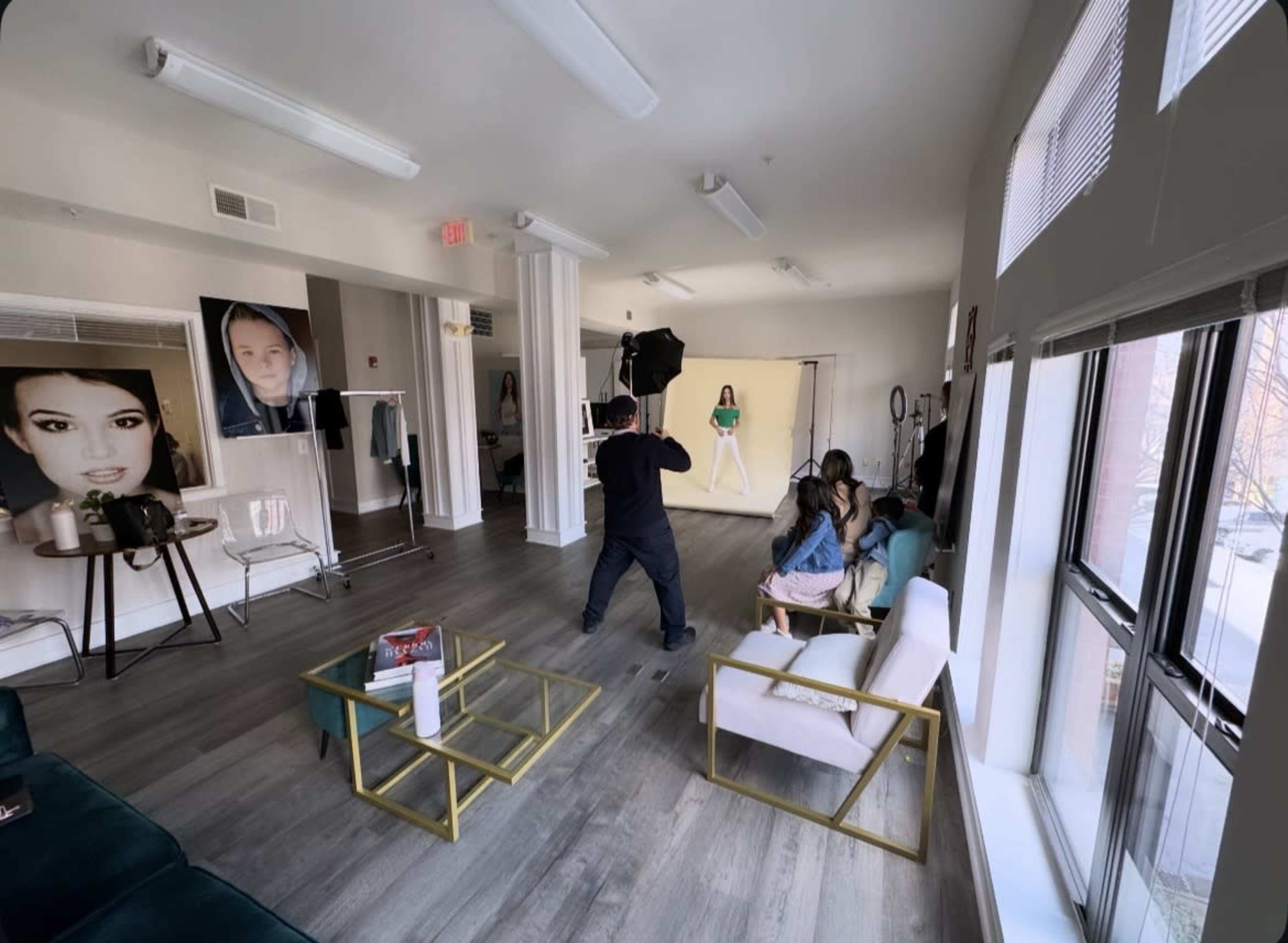 A photographer is capturing images of a model in a studio featuring large photographs on the walls and modern furnishings.