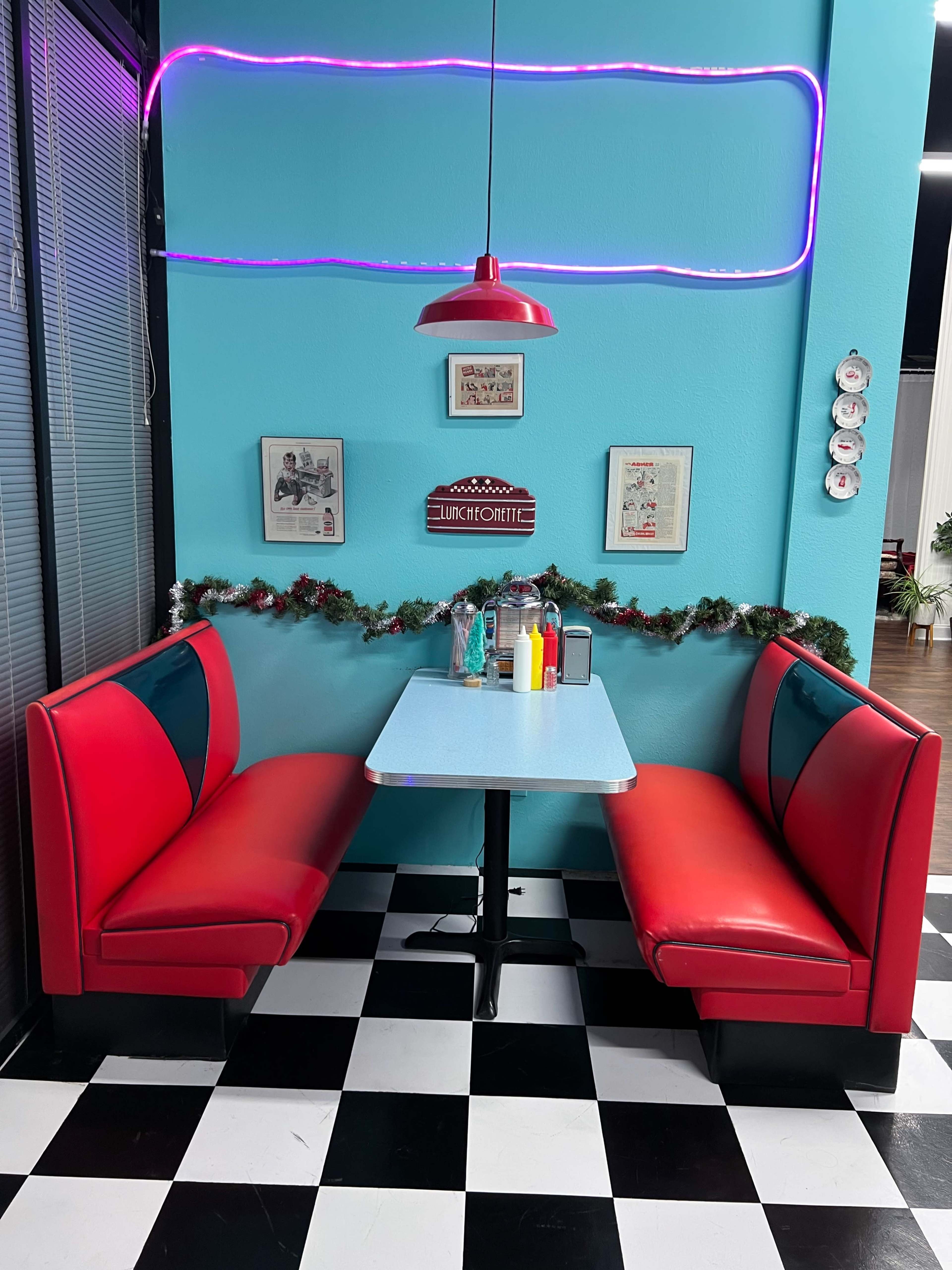 A retro-style diner booth with red and blue seating, a blue tabletop, and condiments arranged on the table.