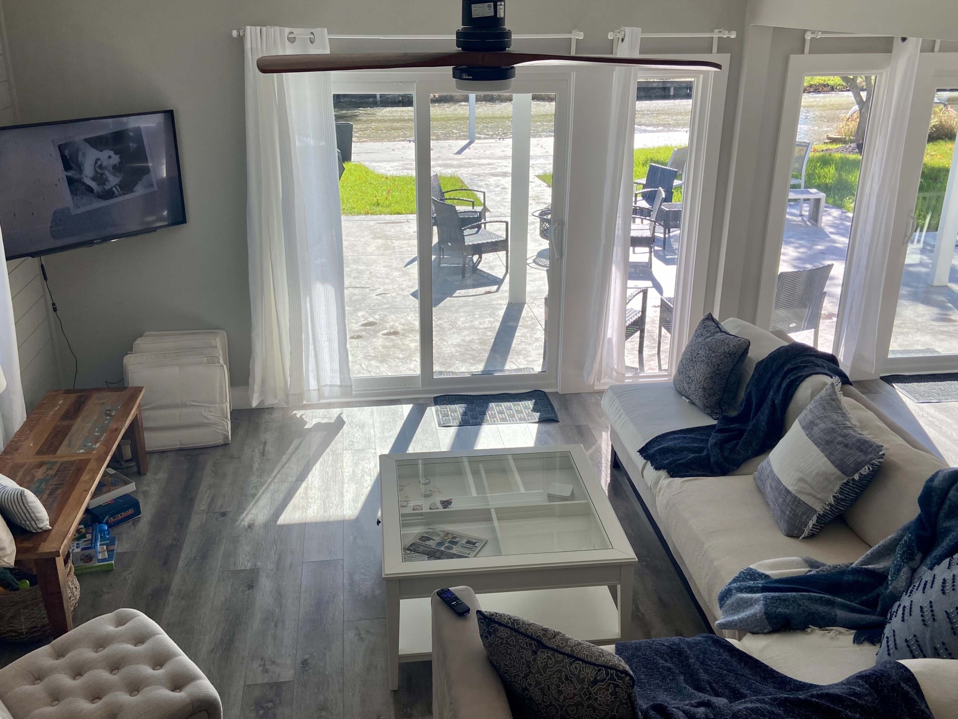 A living room features a sectional sofa, a glass coffee table, and large windows that open to an outdoor patio area.