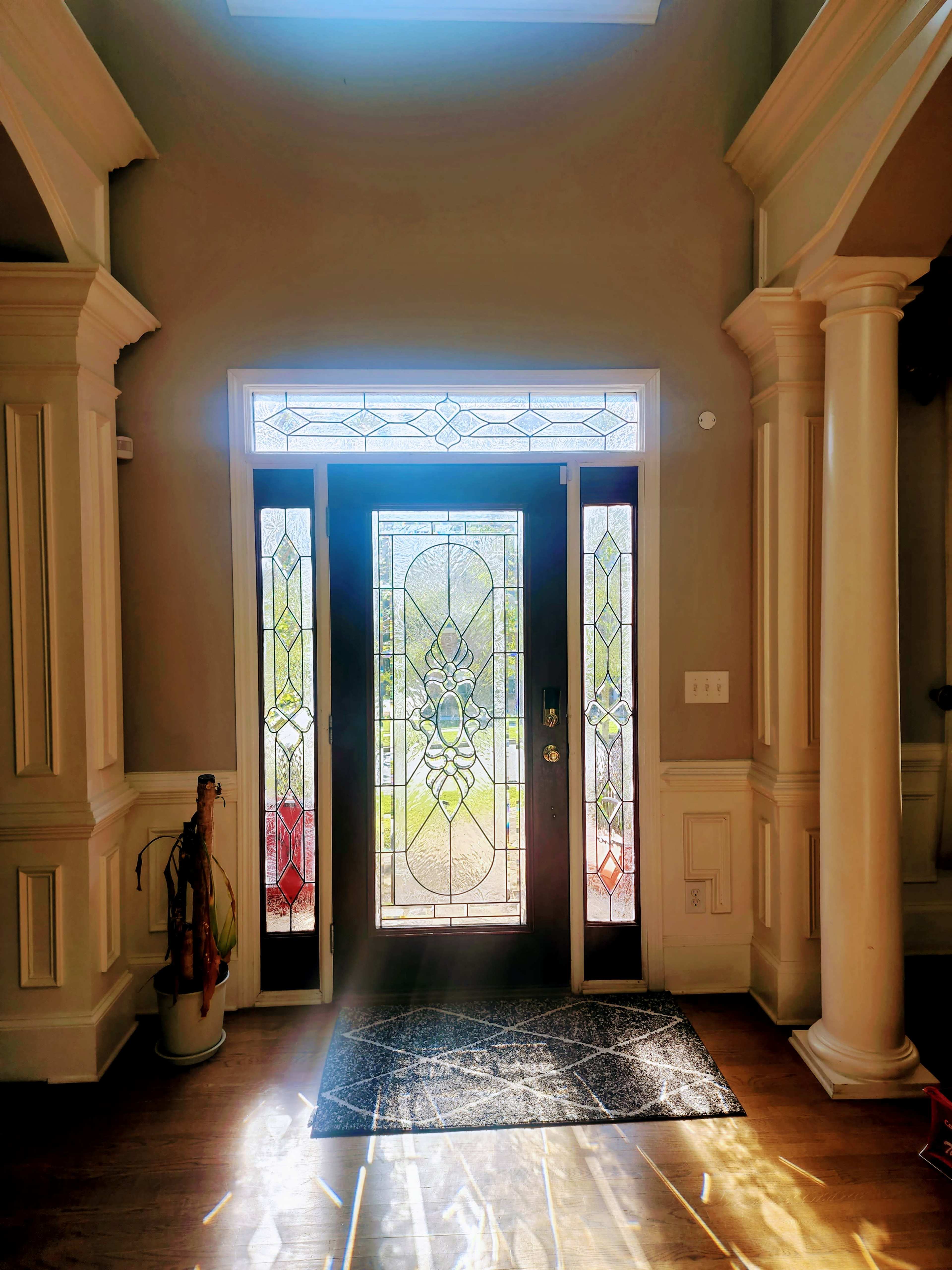 A well-lit entryway with a decorative stained glass door and columns on either side.