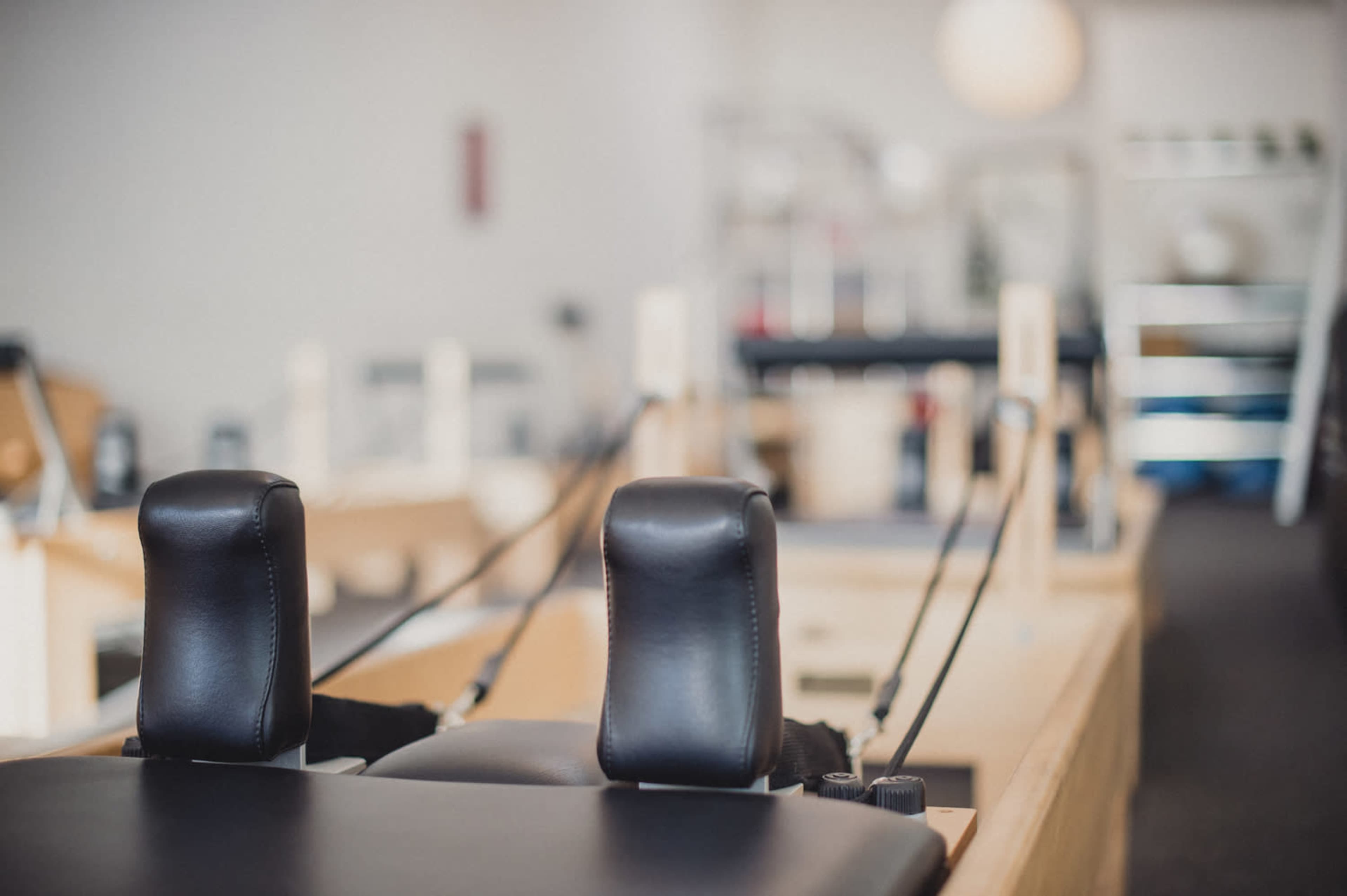 The image shows a close-up view of a Pilates reformer machine in a studio setting.