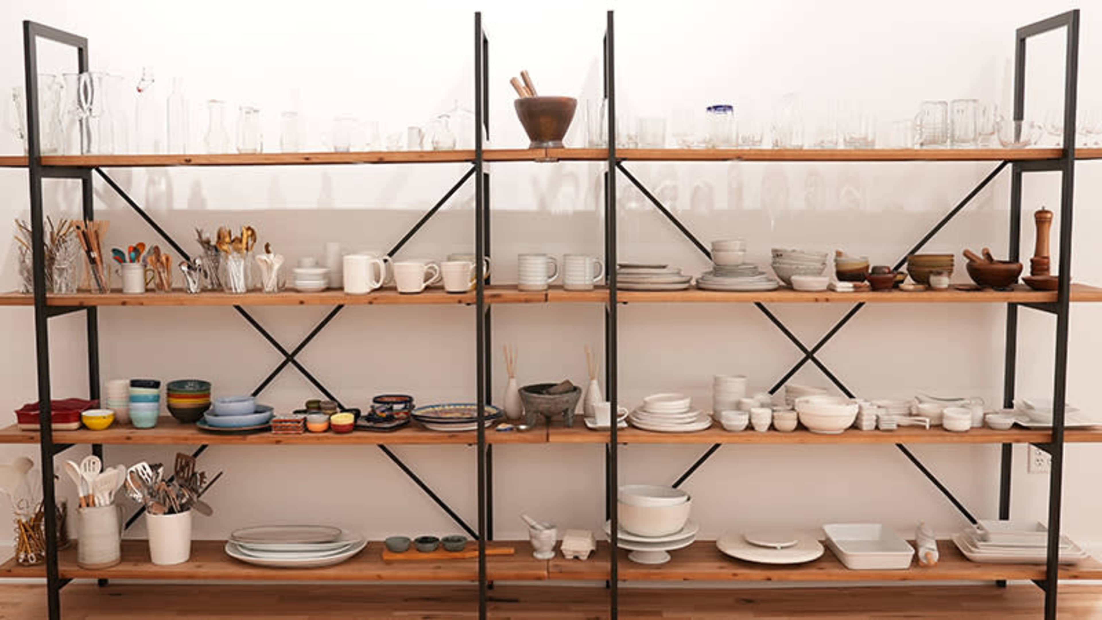 The image shows multiple shelves displaying various kitchenware, including glasses, bowls, plates, and utensils, arranged neatly in a organized manner.