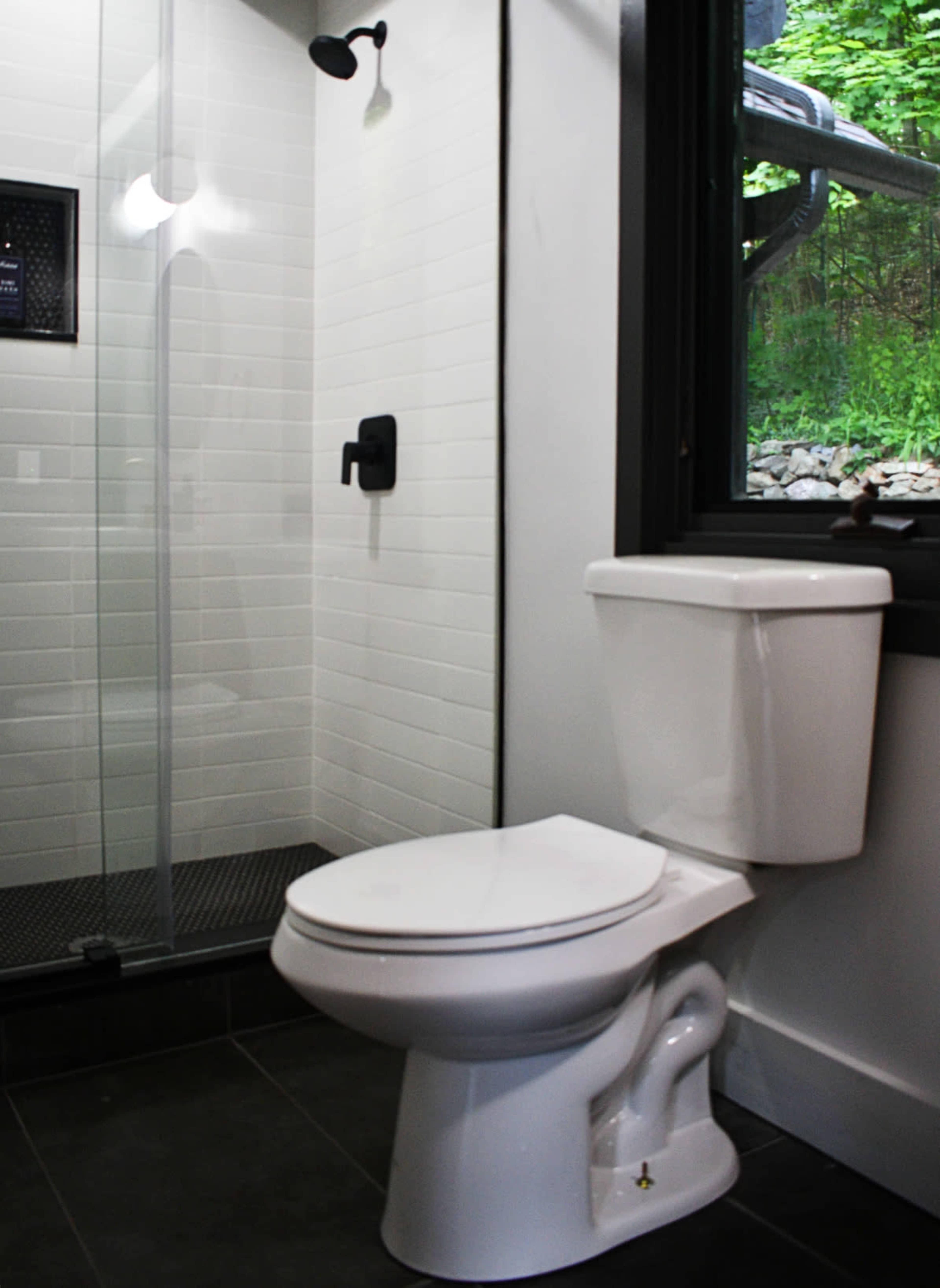 A modern bathroom featuring a white toilet next to a glass shower enclosure with a black showerhead.
