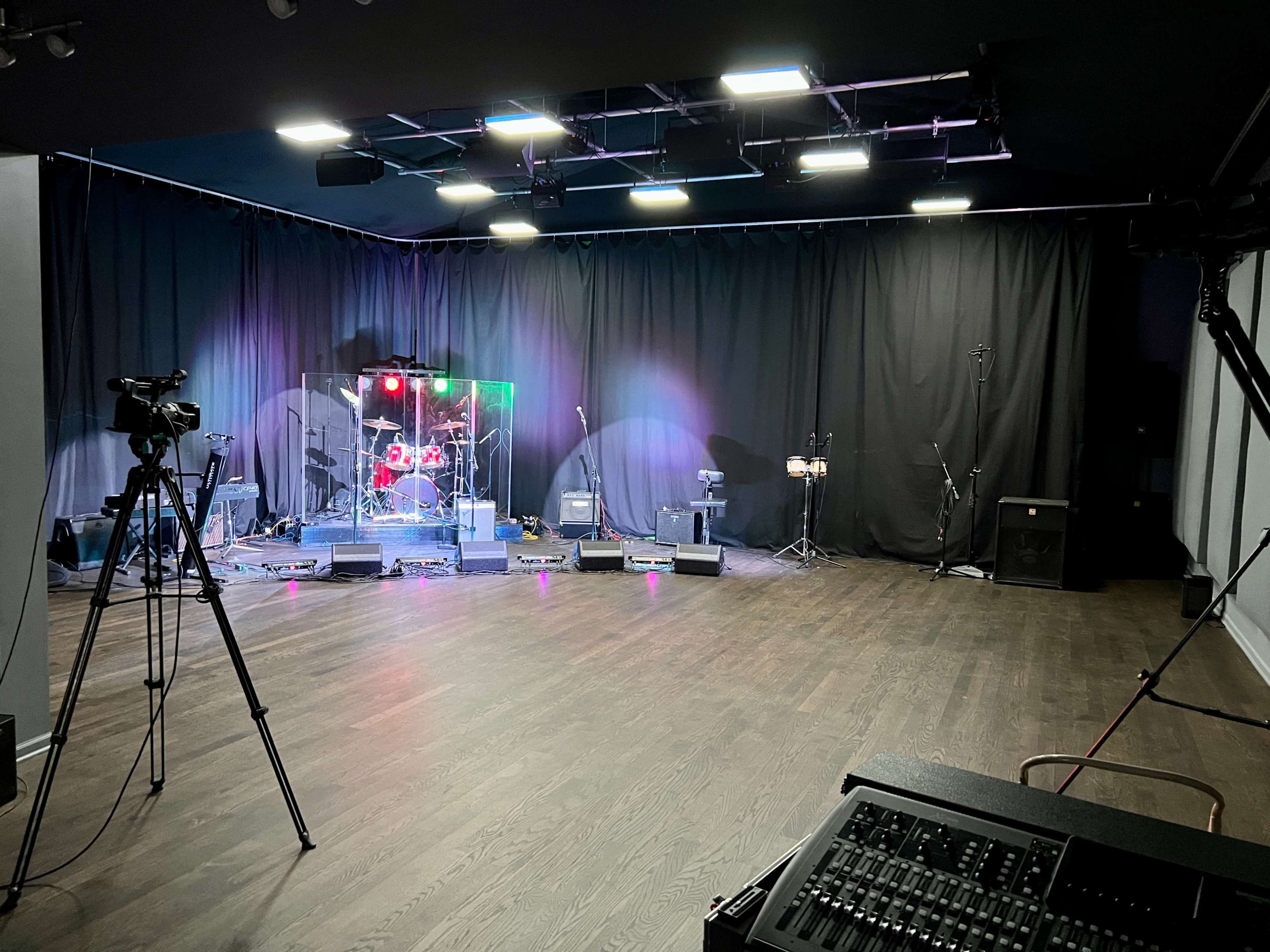 A stage setup with musical instruments, microphones, and cameras in a dimly lit room.