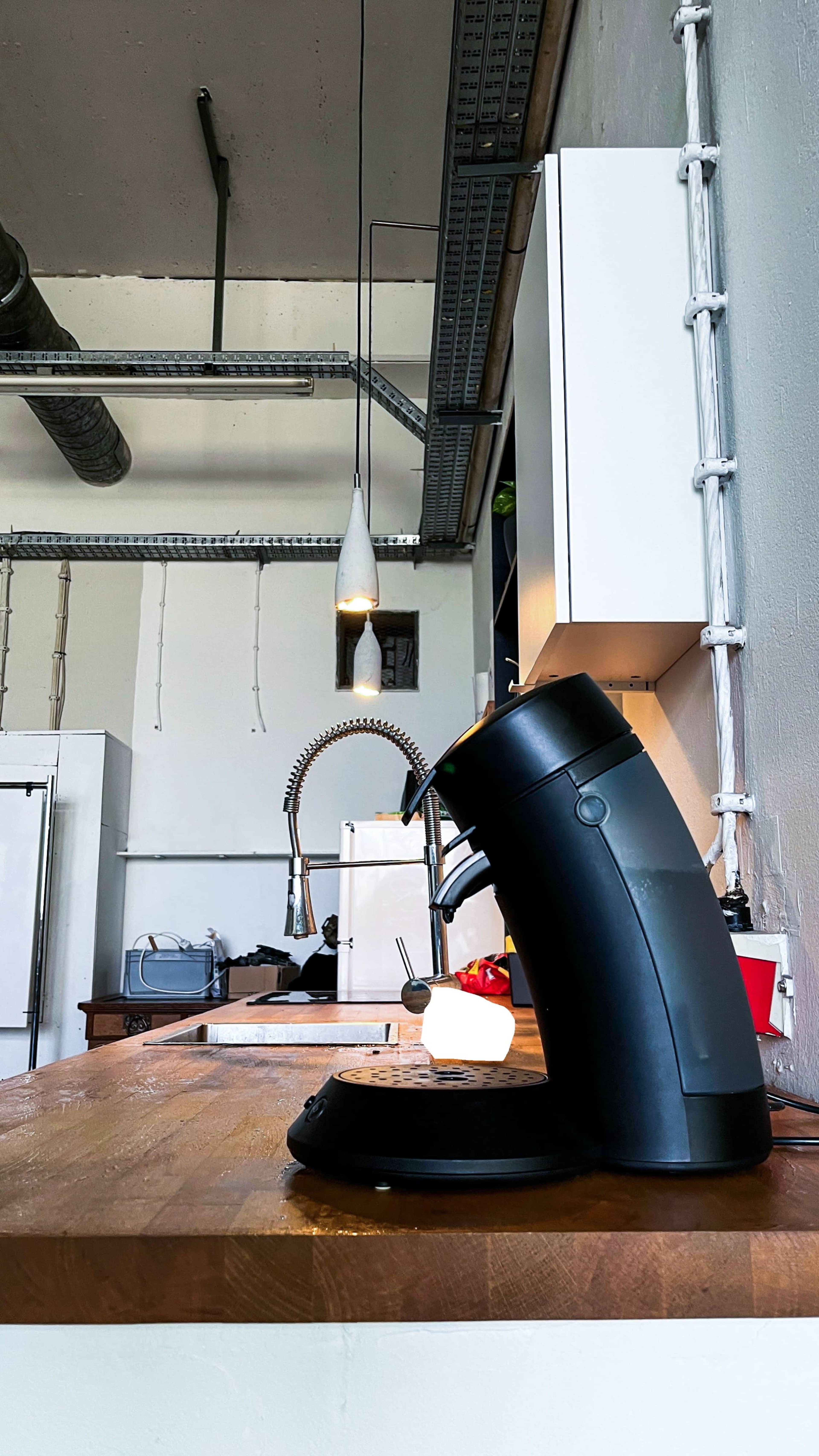 A black kettle is positioned on a wooden countertop in a modern kitchen with industrial elements.