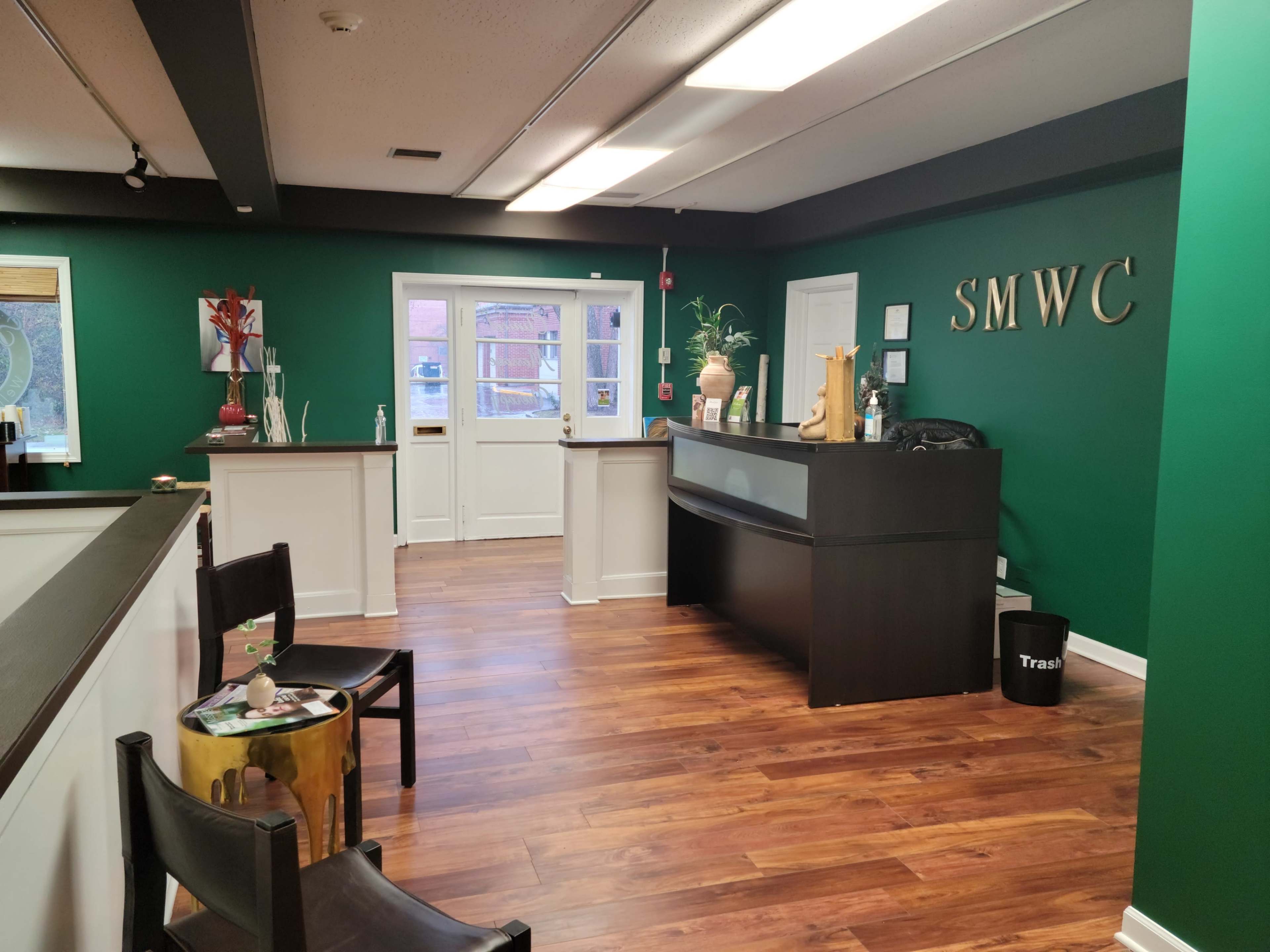 The interior of a reception area features green walls, a front desk, a chair, and a doorway leading outside.